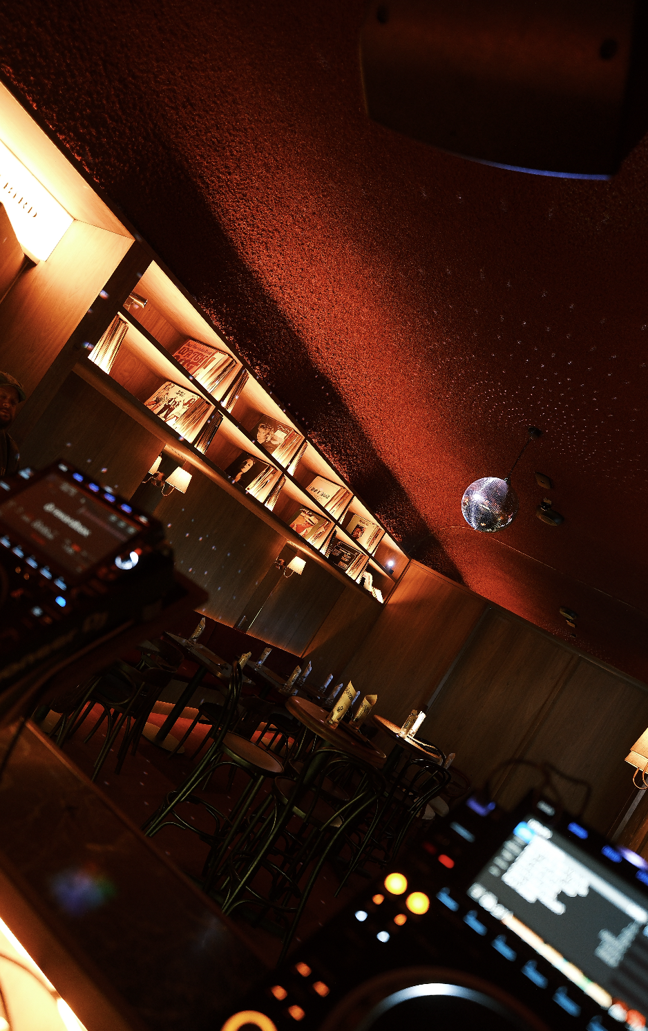 A cozy restaurant or bar with warm lighting, wooden furniture, and a disco ball hanging from the ceiling.
