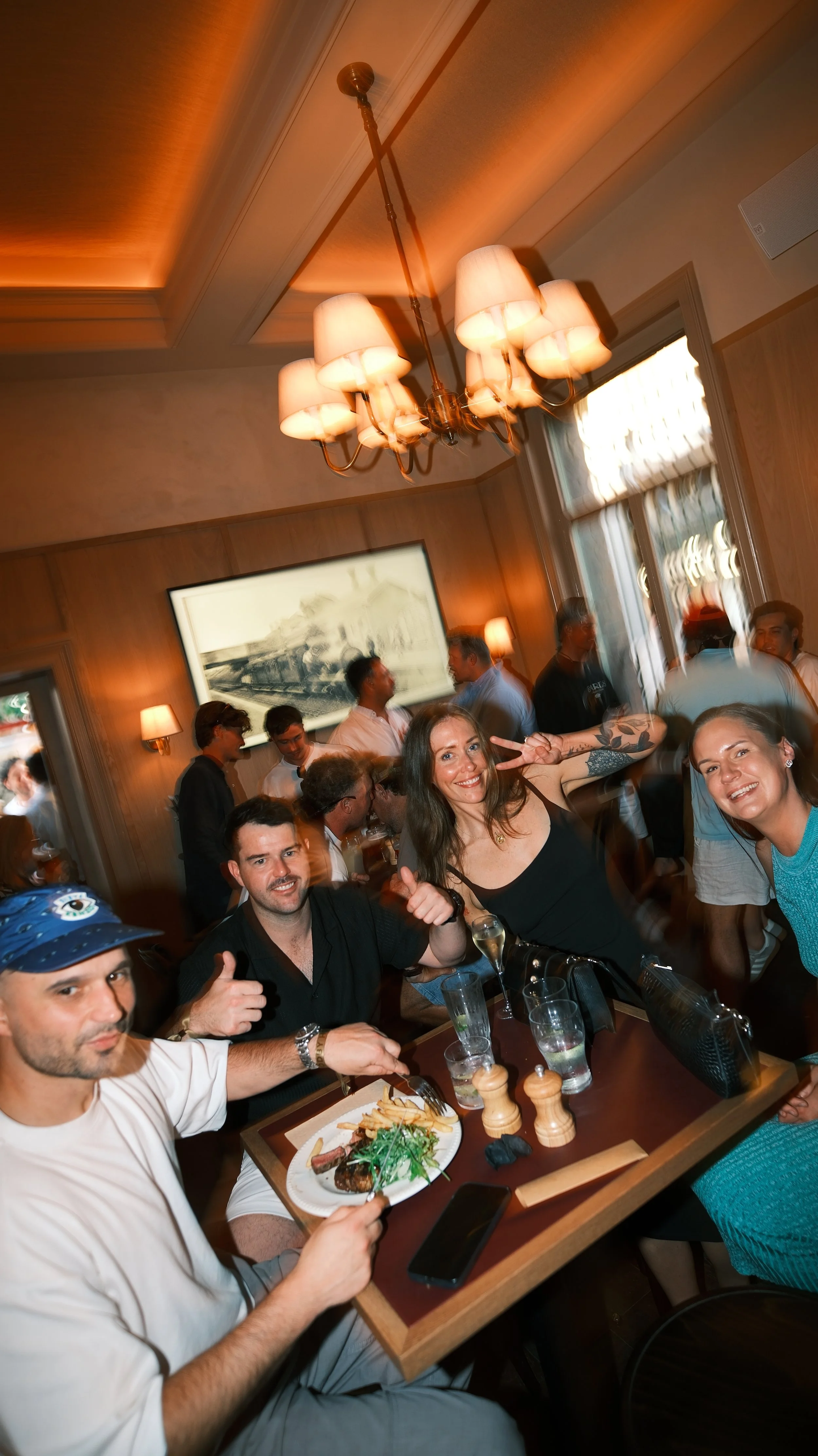 Group of friends enjoying a meal and drinks at a restaurant during a lively gathering.