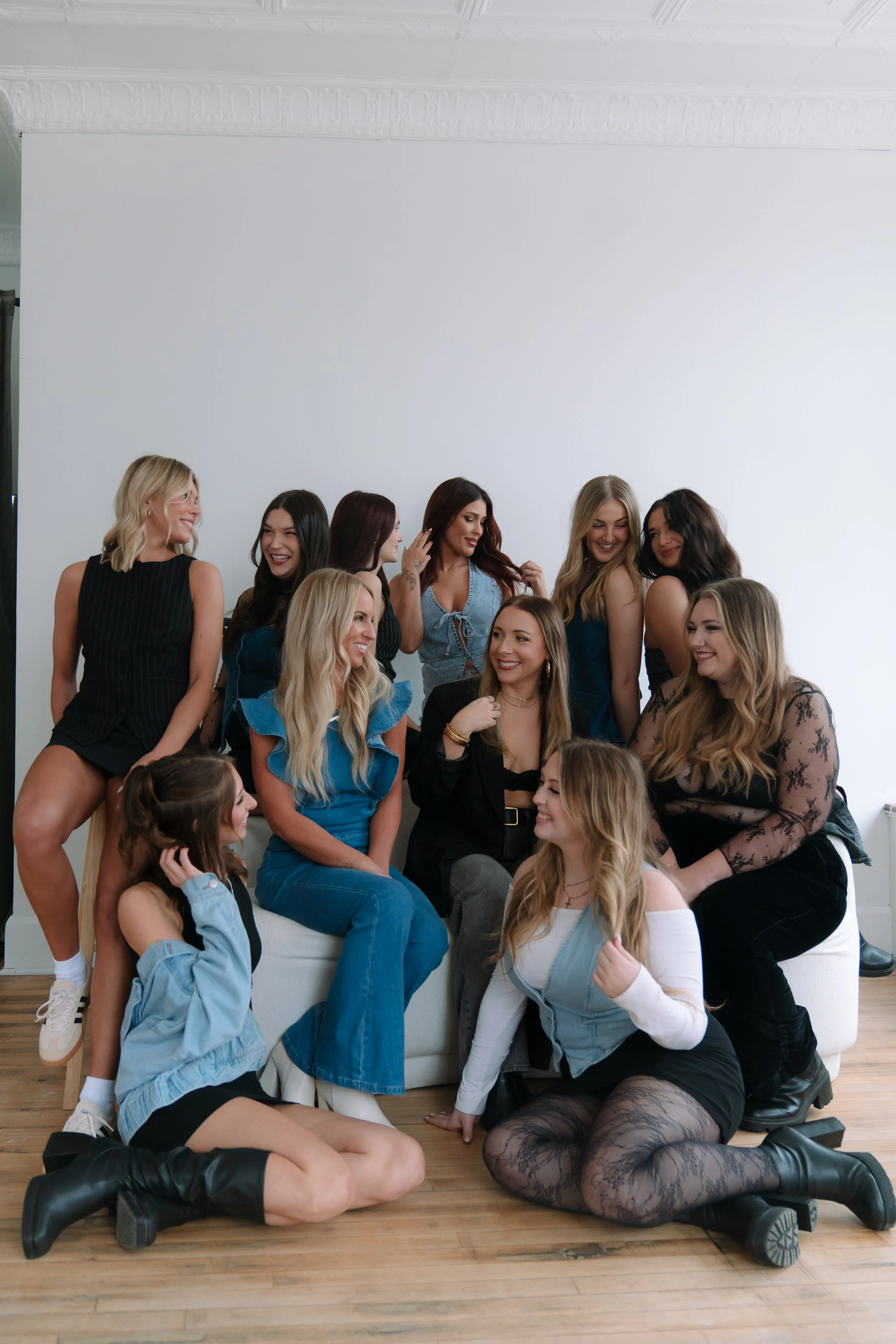 Group of women and girls sitting and standing in a casual indoor setting, enjoying conversation and smiling.