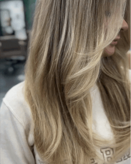 Close-up of a woman with long blonde hair wearing a light-colored shirt.