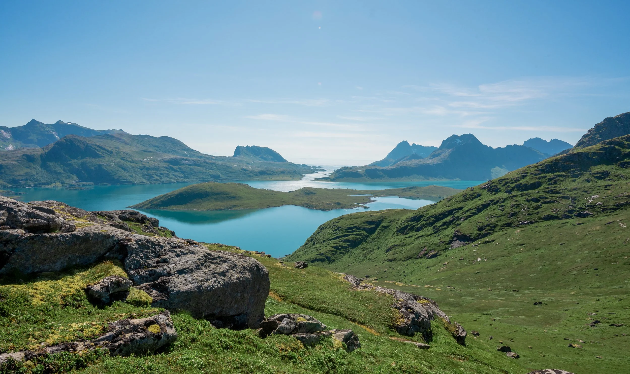 Scenic view of a mountain lake with green hills and rugged mountain peaks in the background