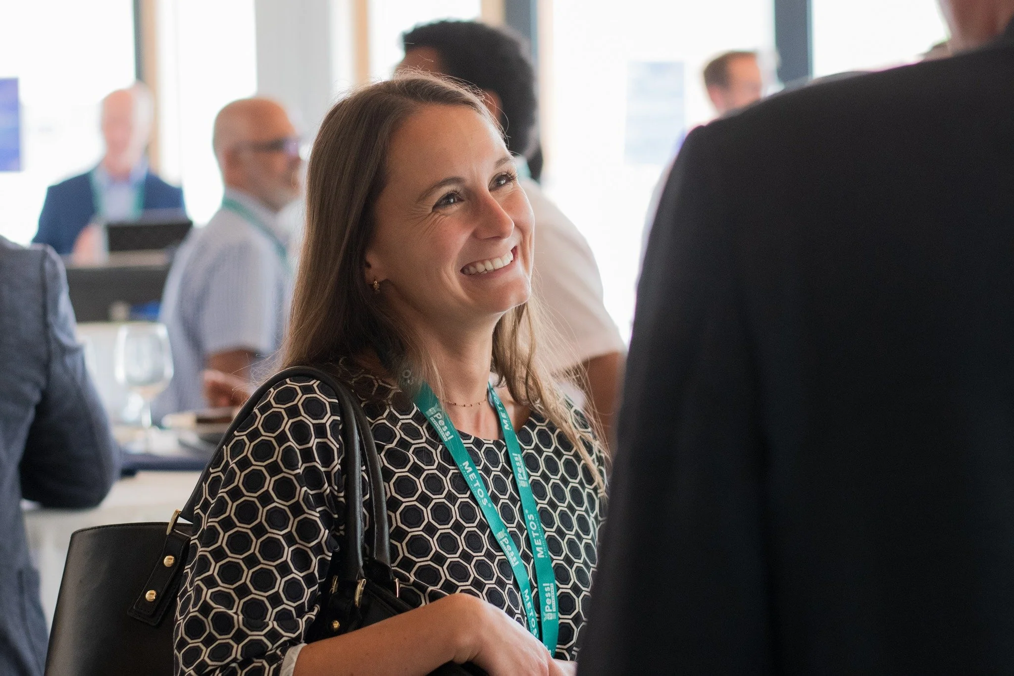A woman with long brown hair smiling during a professional networking event.