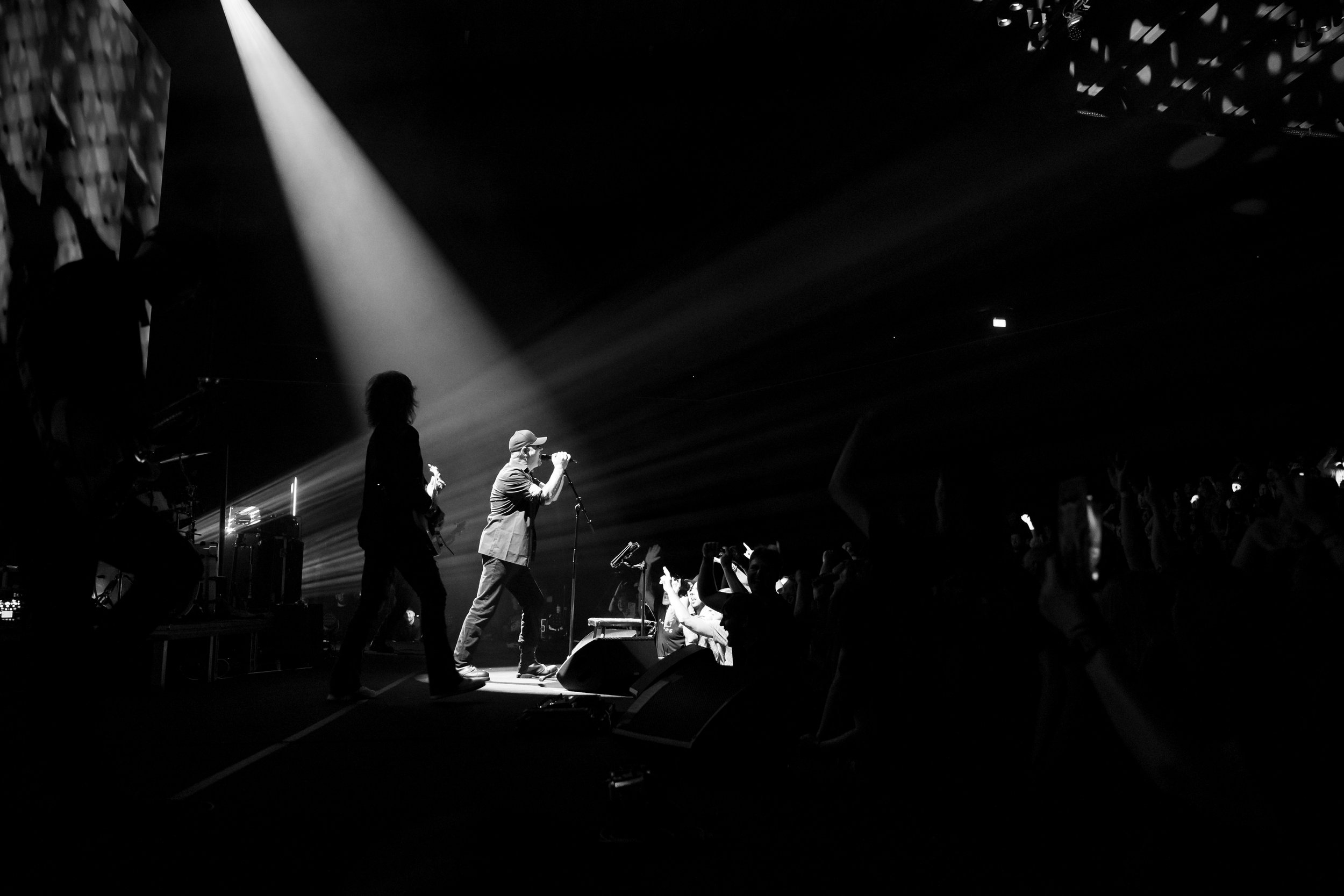 Black and white photo of a live music concert with a band performing on stage and an audience watching.
