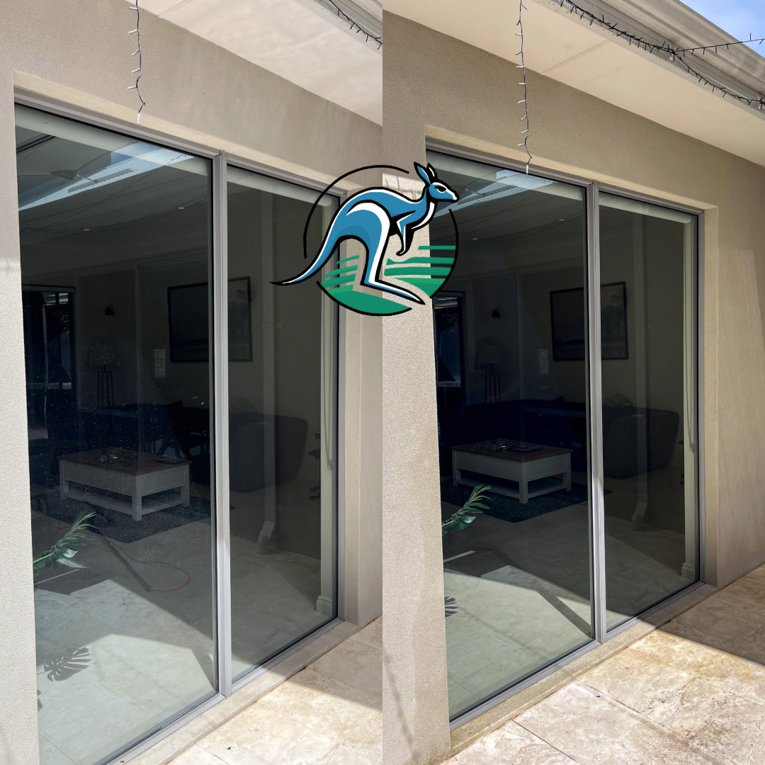 Two side-by-side sliding glass door panels on a beige building exterior, with interior view of a living room visible through the glass.