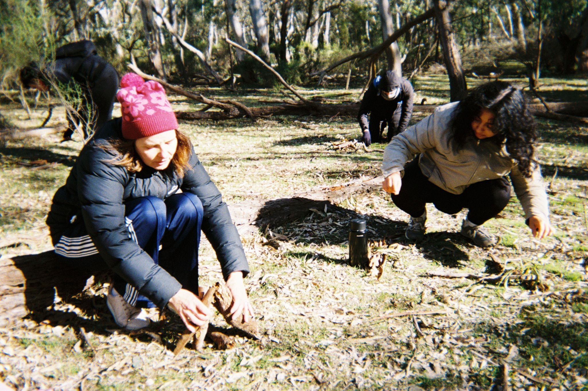 3 people doing a nature connection activity making structures from things on the ground