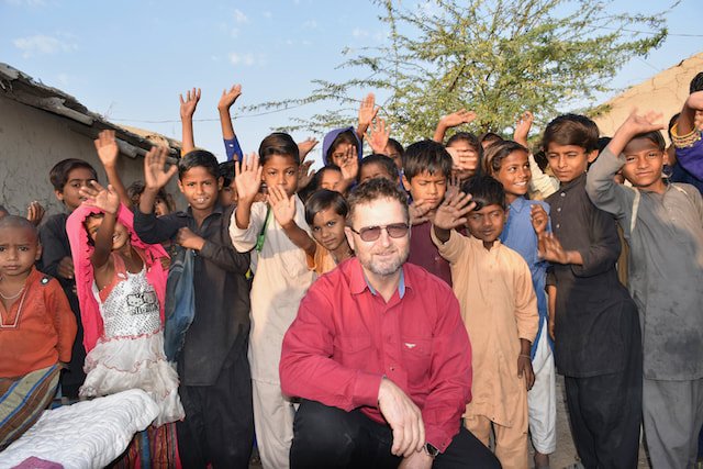 children and organisation founder waving and raising their hands in a rural community