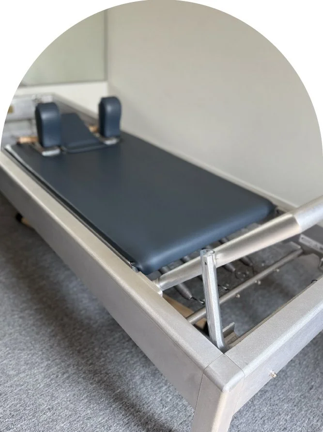A medical gurney or stretcher with a black padded surface and adjustable side rails, placed in a clinical setting with a gray carpeted floor.