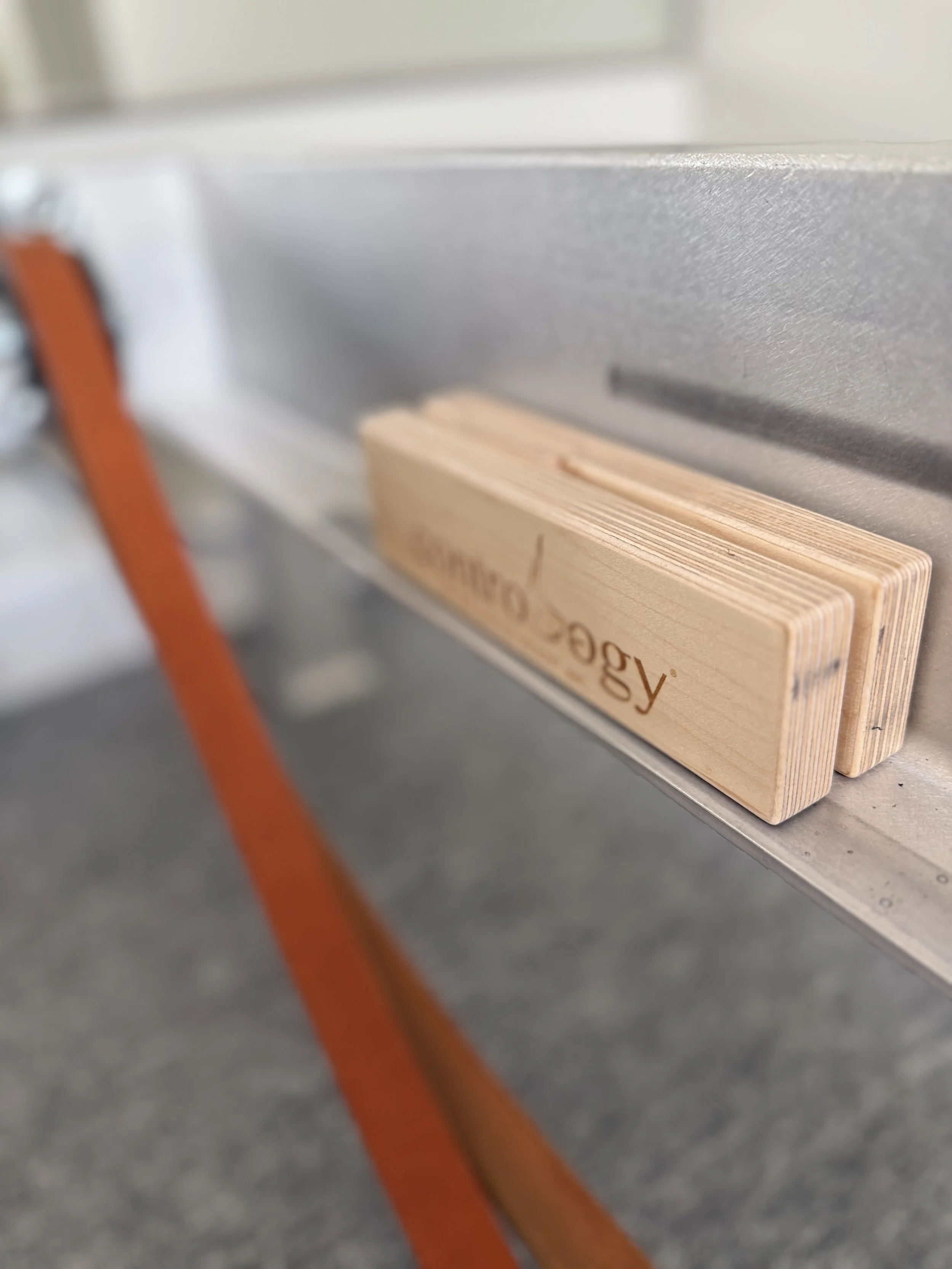 Wooden block with the word 'Geology' engraved on it, placed on a metal surface.