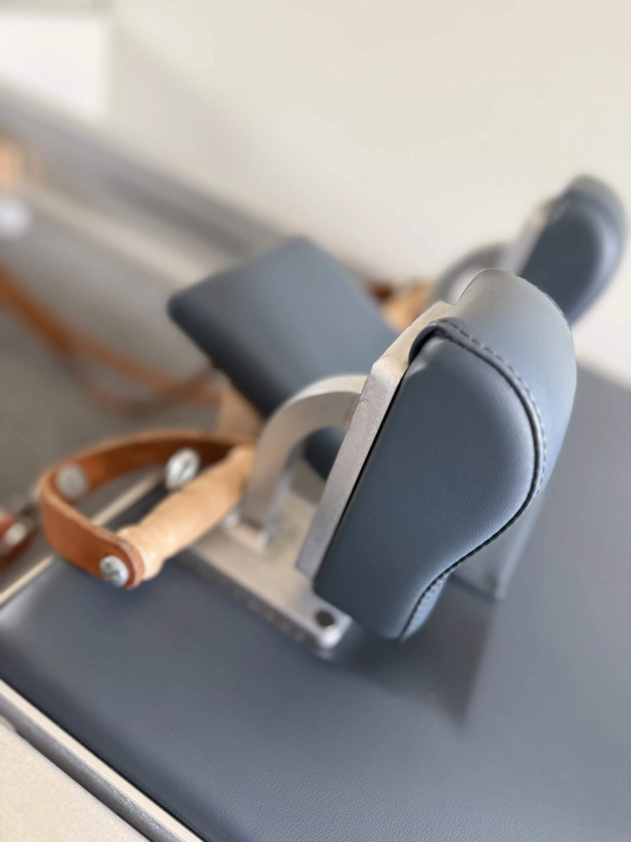 Close-up of a gray airplane seat with a brown leather tray table in the upright position.