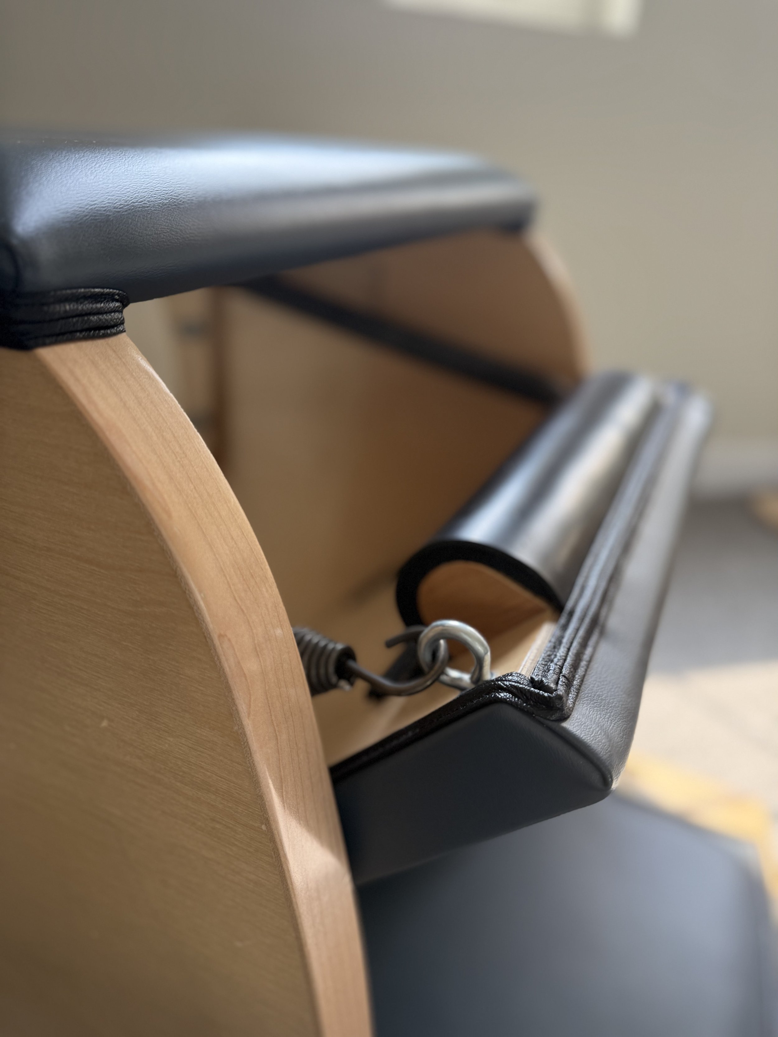 Close-up of a leather-upholstered and wooden gymnastic vaulting horse with a metal spring and hinge mechanism.