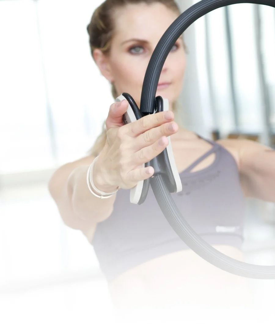 A woman holding a yoga or exercise ring in a gym or fitness studio.