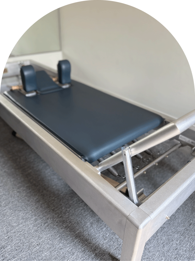 A medical examination or treatment table with a black cushioned surface and two adjustable padded supports at the head, located in a clinical setting.