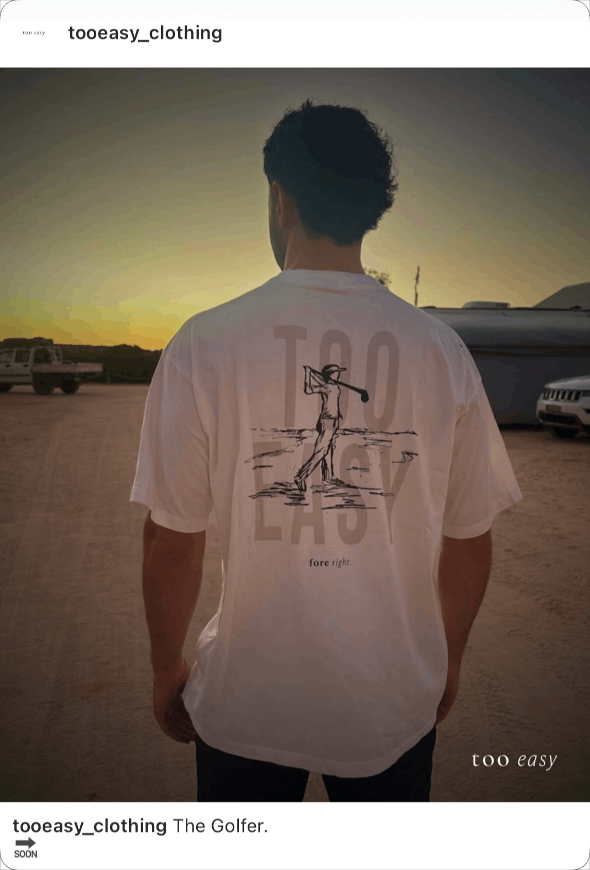 A person wearing a white T-shirt with a line drawing of a golfer swinging a club, standing on a beach at sunset, with cars in the background.