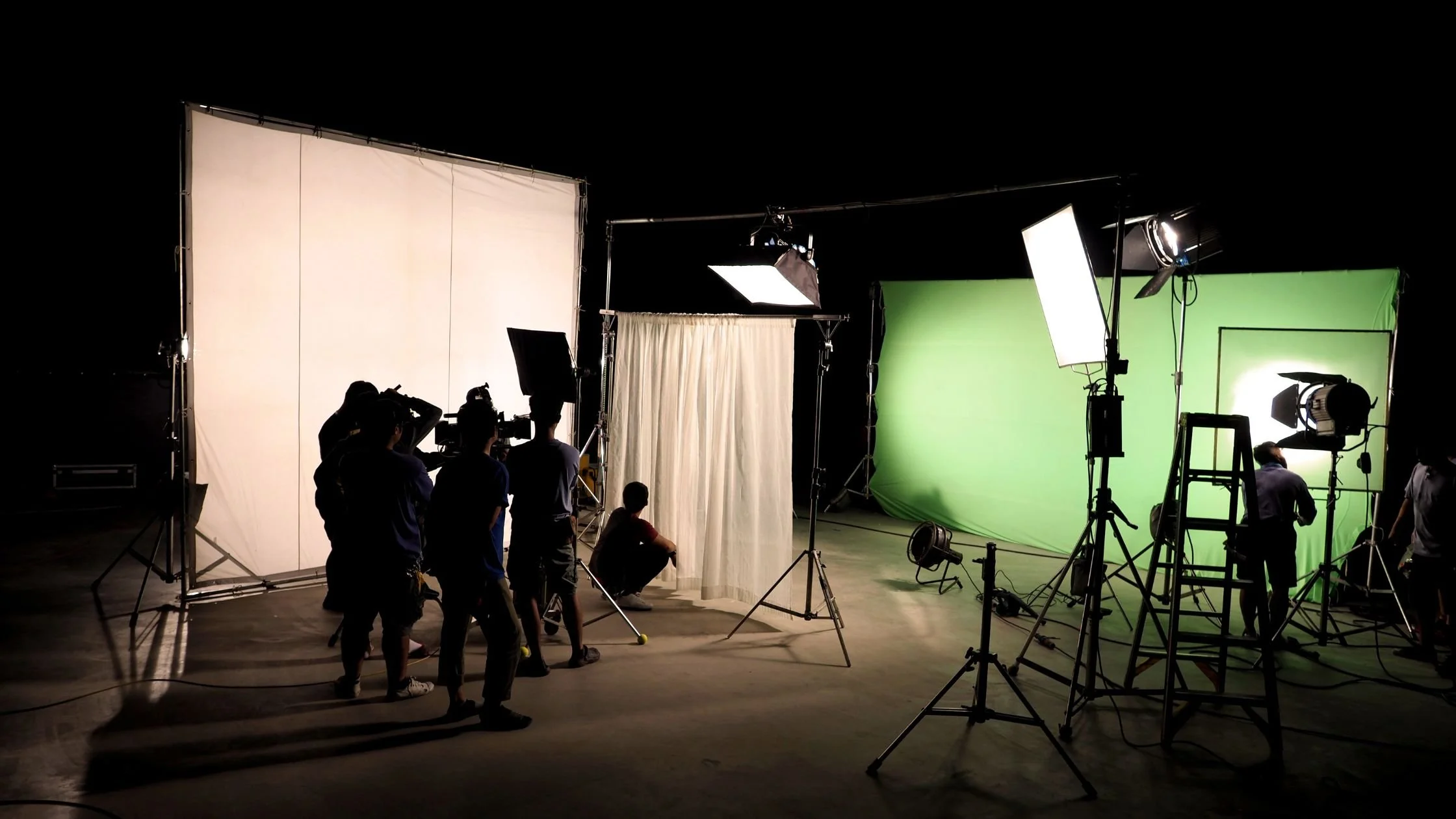 Film crew on set with lighting and green screen.