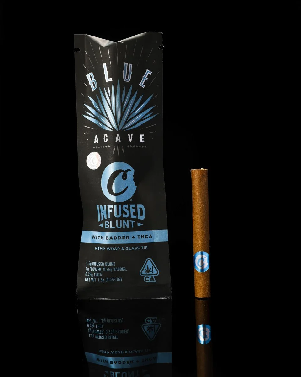 Package of Blue Agave infused blunt with hemp wrap and glass tip, with a single blunt next to it on a reflective black surface.