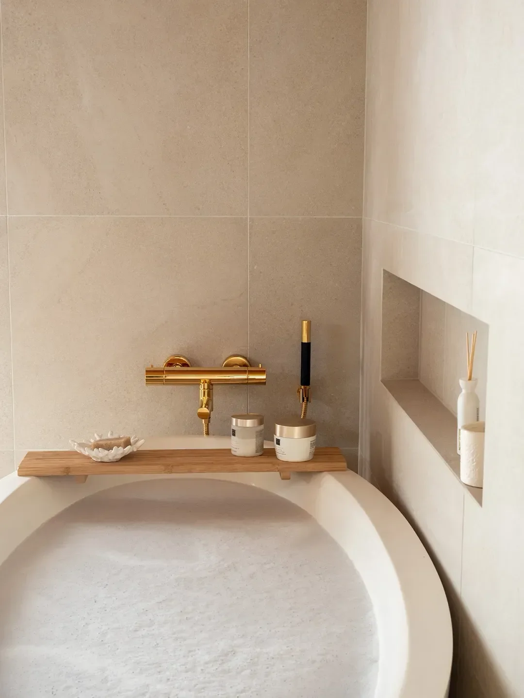 Isot beiget laatat ja kaunis kylpyamme. Kultaiset yksityiskohdat tekevät tilasta ylellisen.