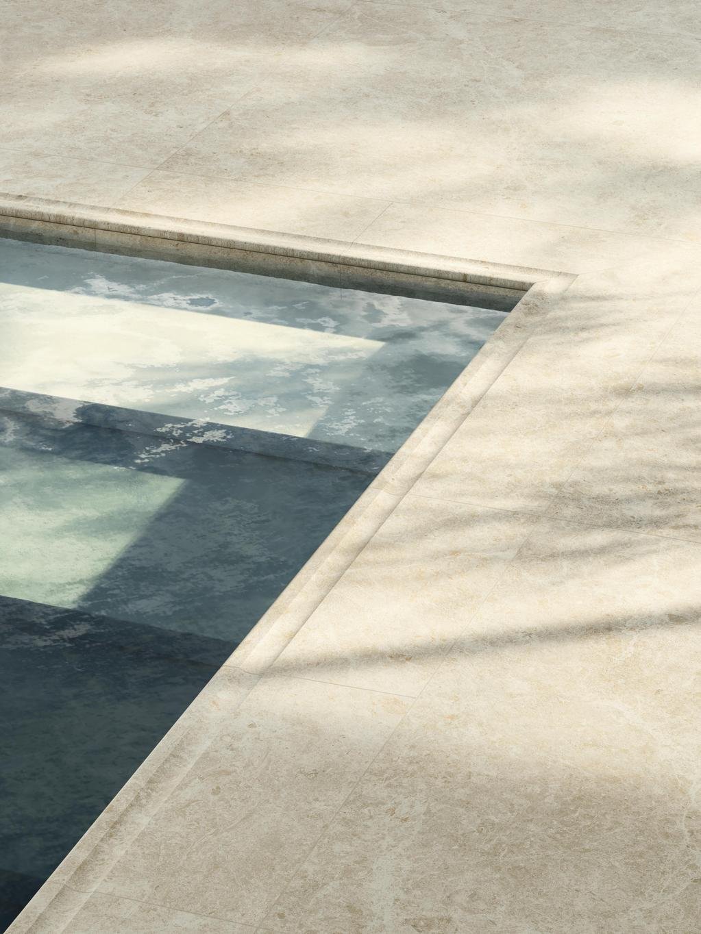 Uima-altaan reuna jossa näkyy upeat isot laatat. Laatat on beigen väriset ja vesi puhtaan sinistä.