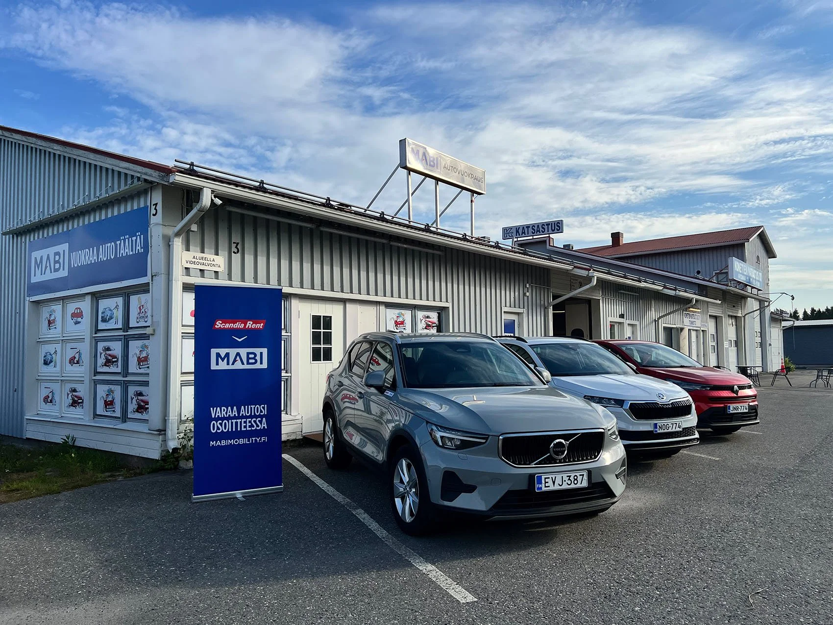 Autoja rivissä toimipisteen edustalla, taustalla logot MABI autovuokraus ja Scandia rent.
