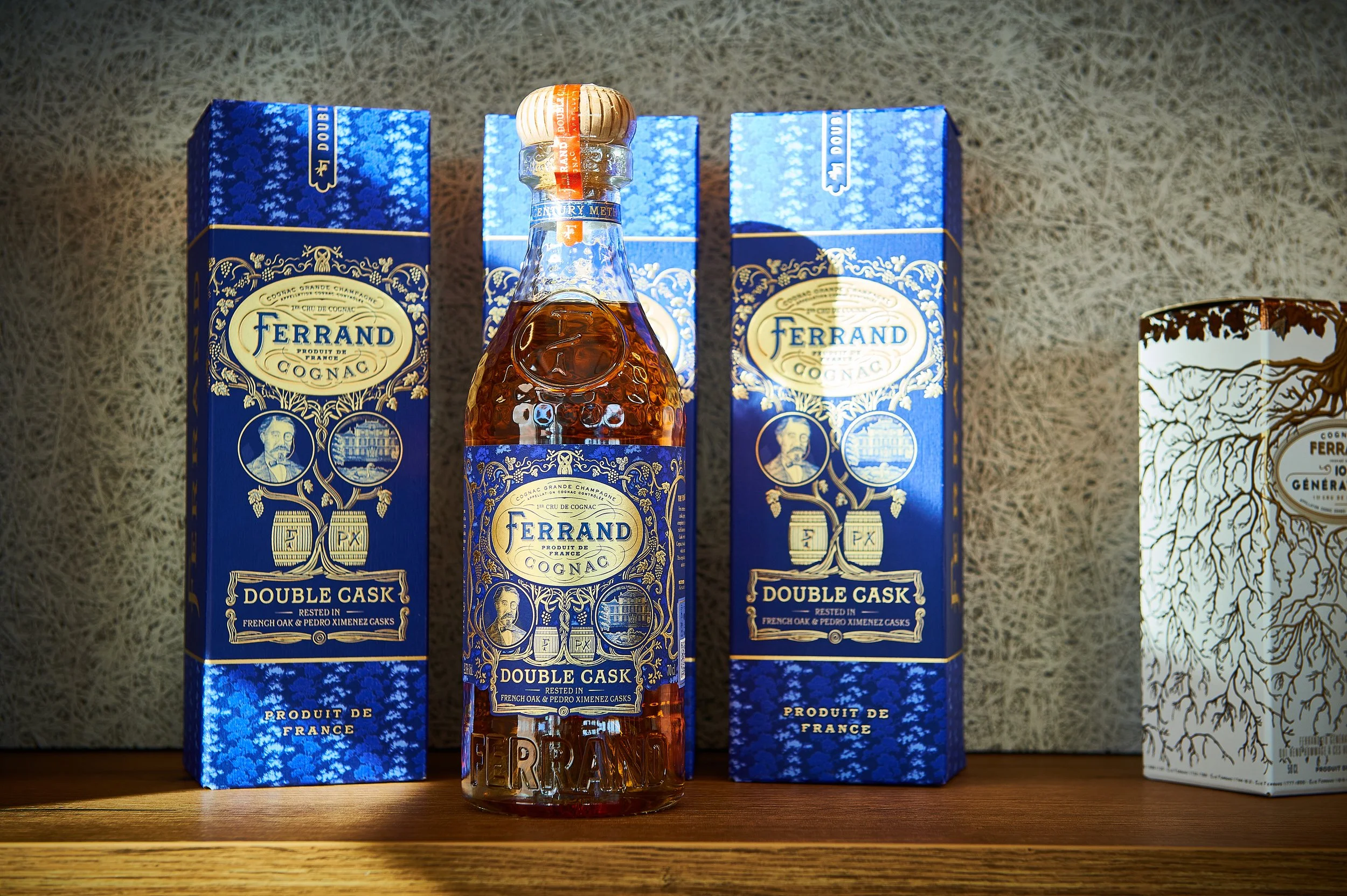 Flasche und Verpackungen des französischen Cognacs Ferrand Double Cask auf einem Holzregal.