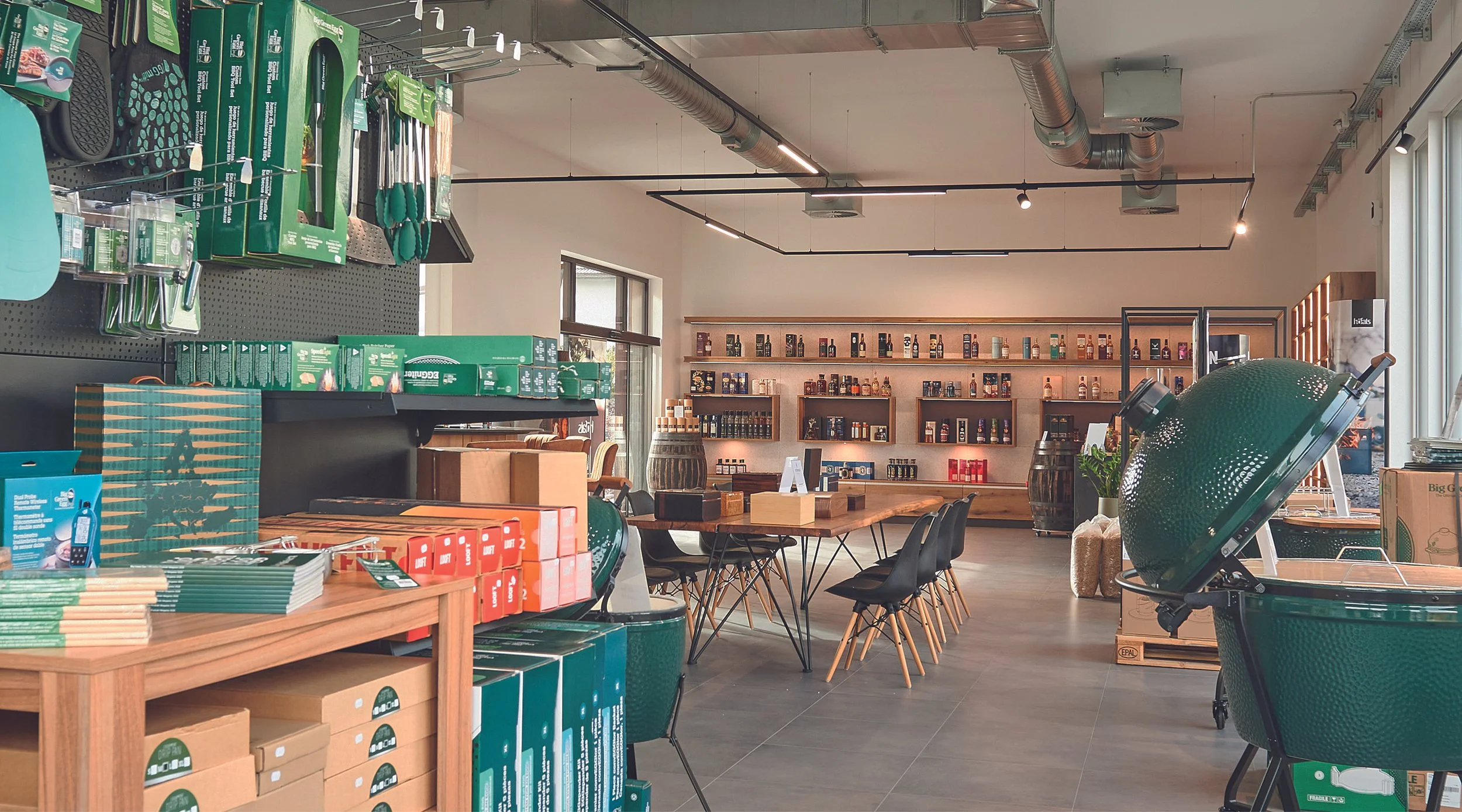 Ein gemütlicher Laden mit Gartenbedarf, inklusive Grill, Tische, Stühle und Produkte auf Regalen.