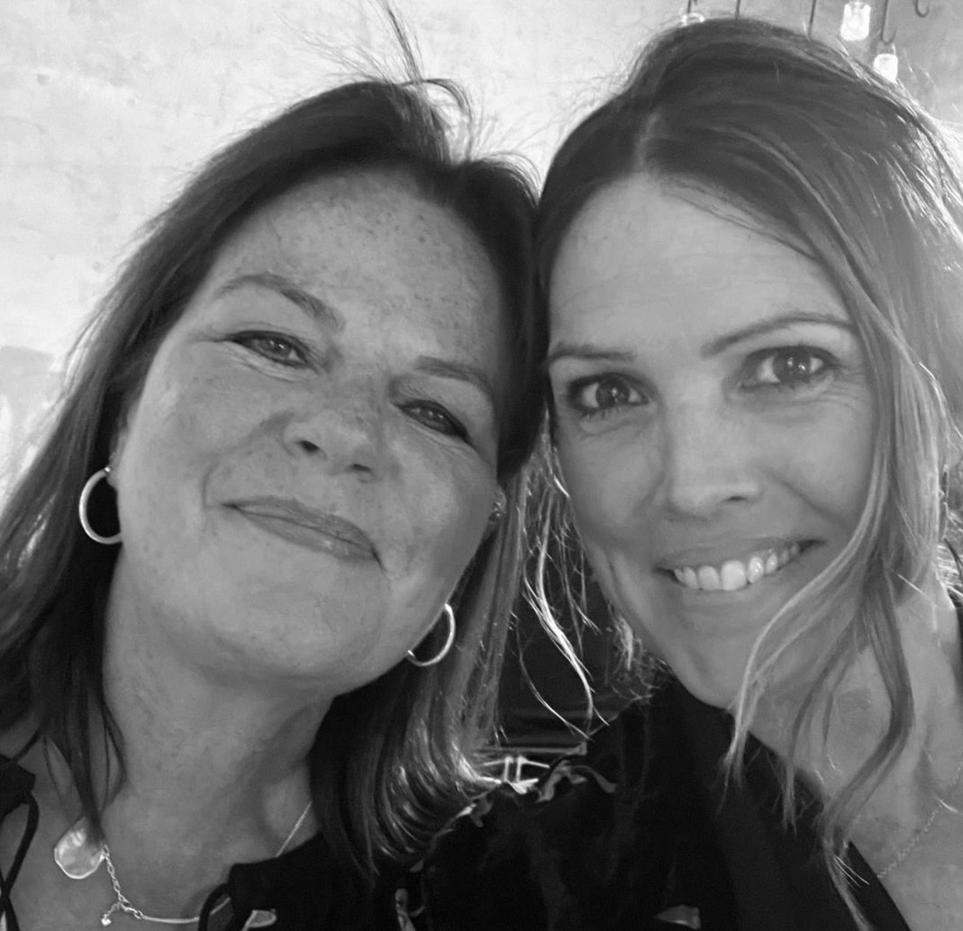Two women smiling closely in a black-and-white photo.