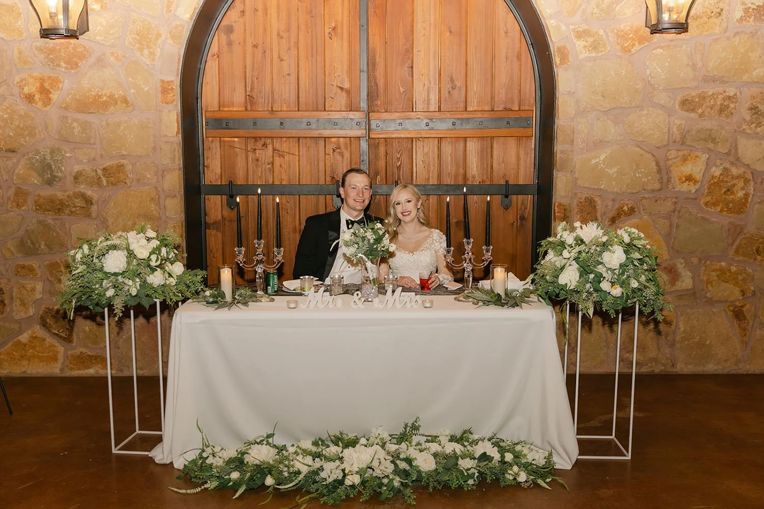 Wedding picture in front of a large wooden Tuscan door and a head table