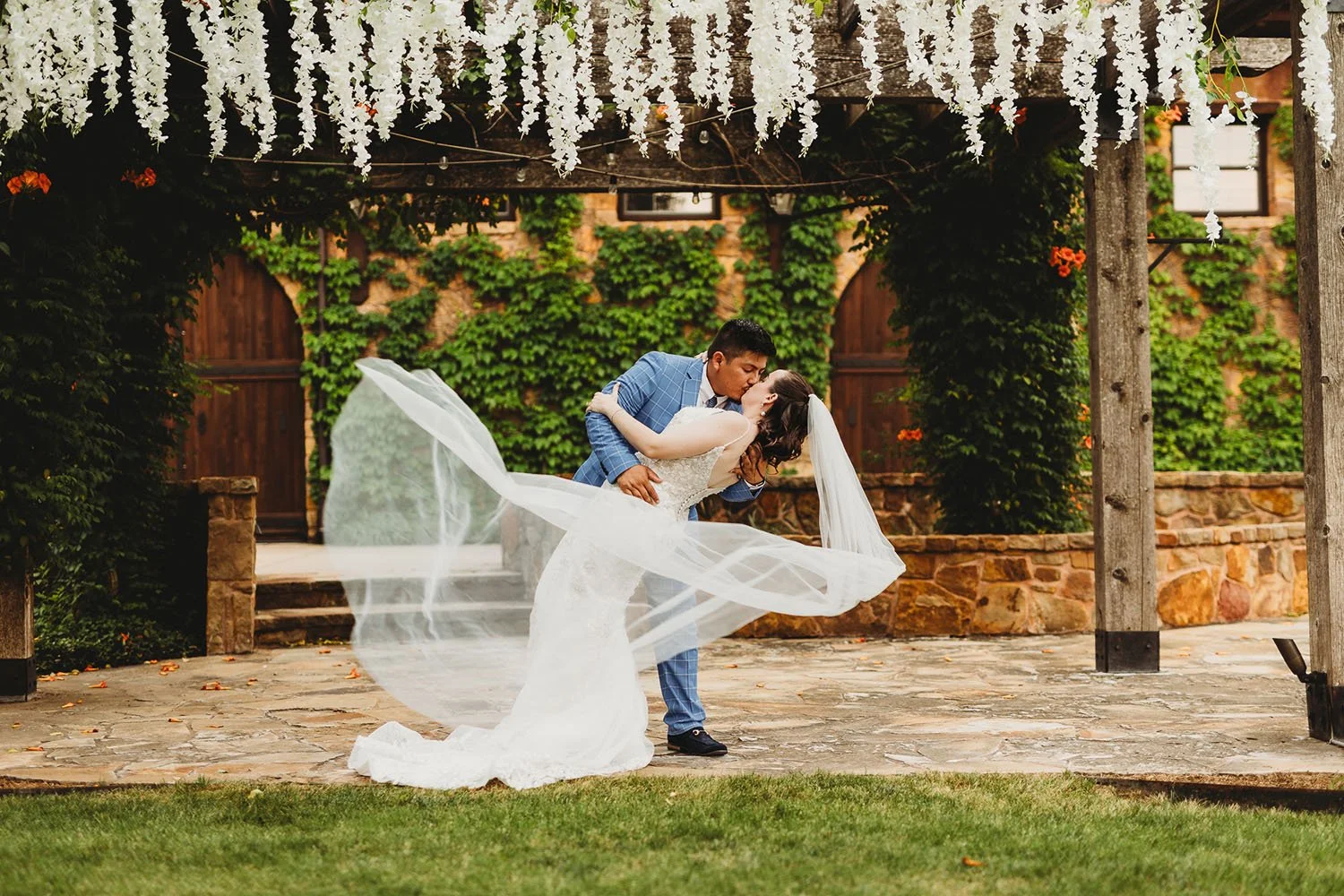 Tuscan style wedding venue with a couple kissing and her veil blowing in the wind