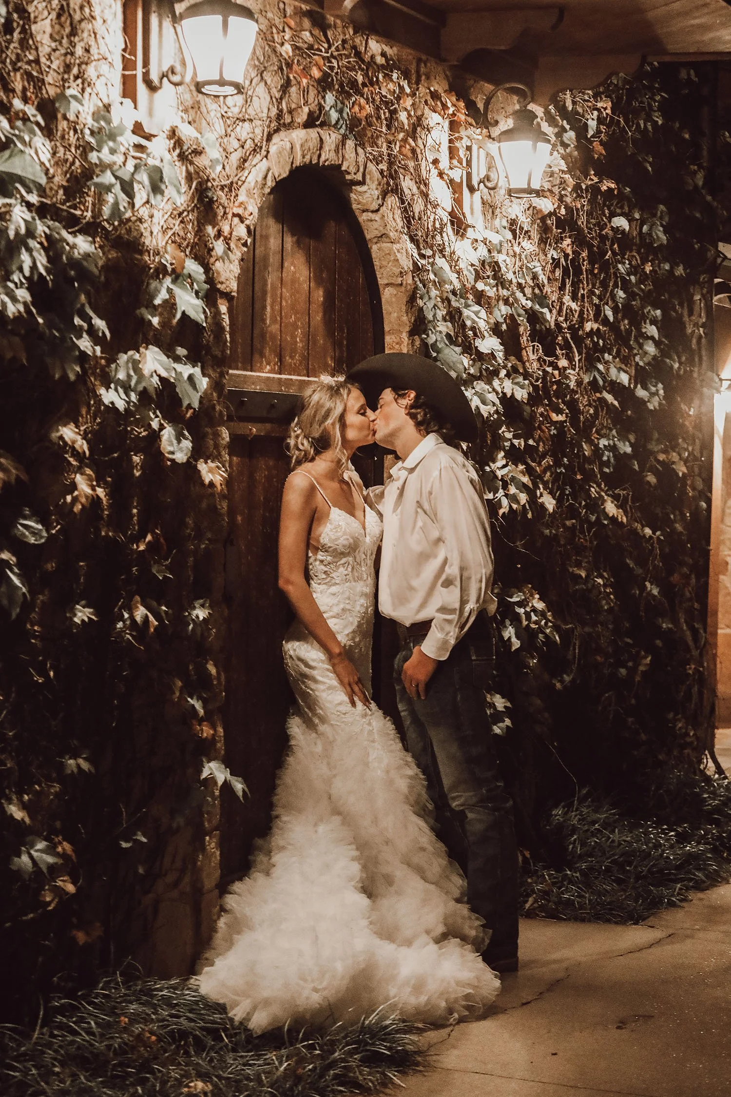 Wedding photo of a couple kissing in front of the Tuscan style building and rustic arched wooden door