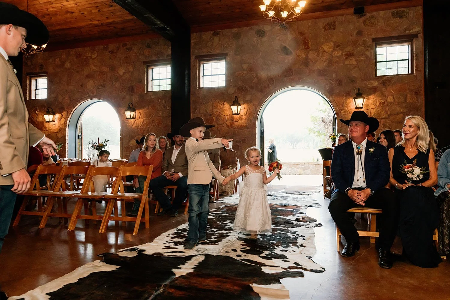 Ring bearer and flower girl walking down the cowhide runner