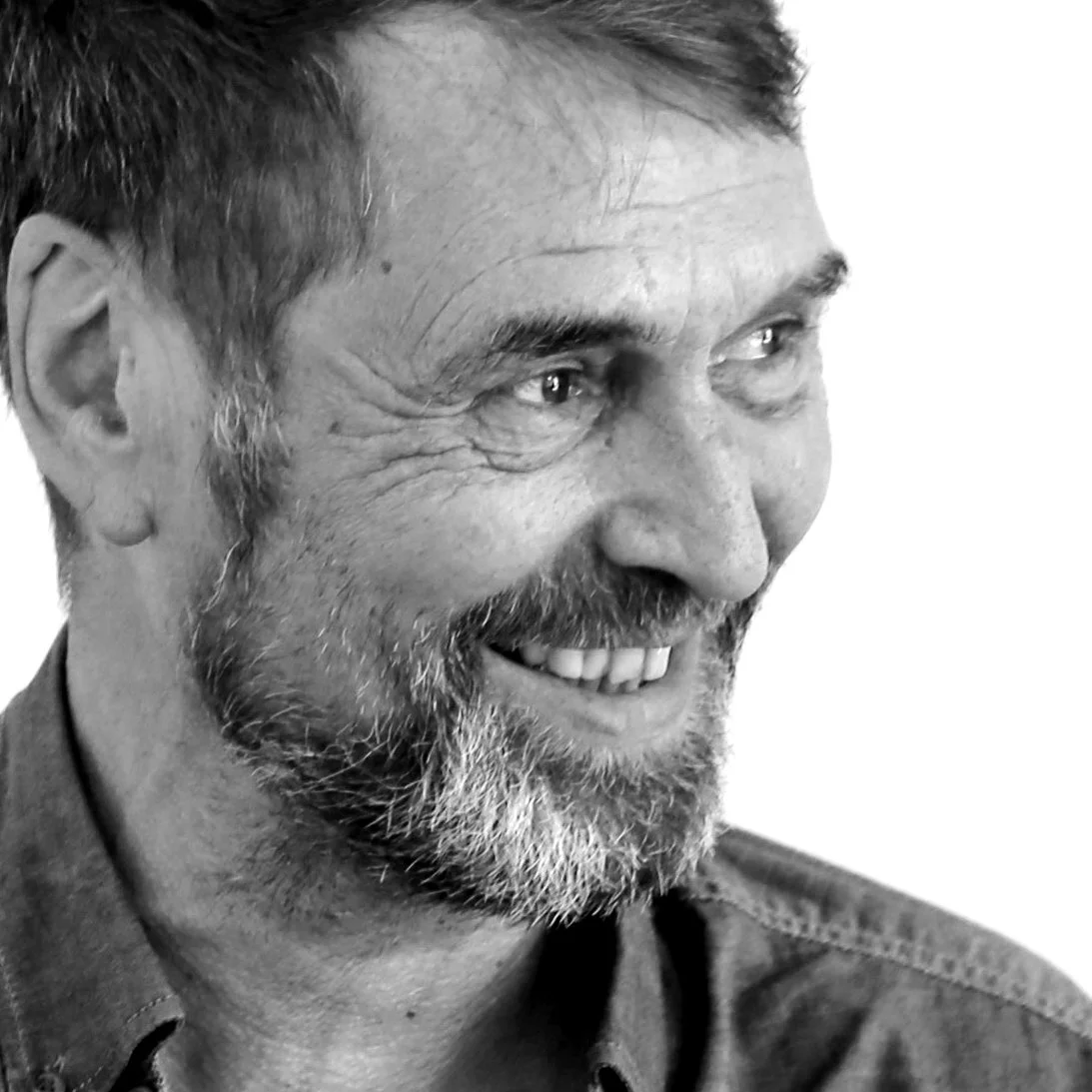 Thomas Degner Close-up black-and-white photograph of a middle-aged man with a beard smiling and looking to his right.