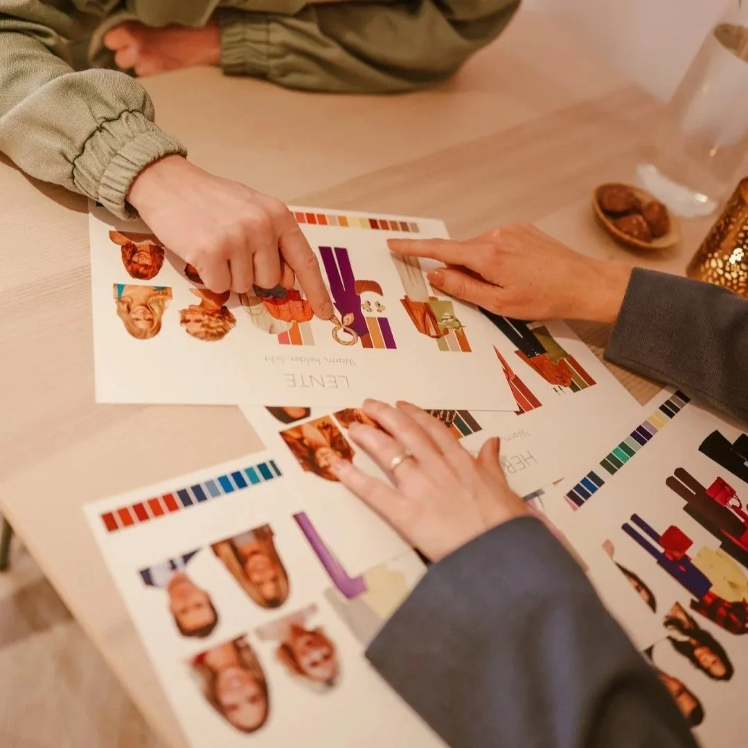 Mensen die op een tafel naar kleurkaarten met portretfoto's en kleurpanelen kijken en wijzen.