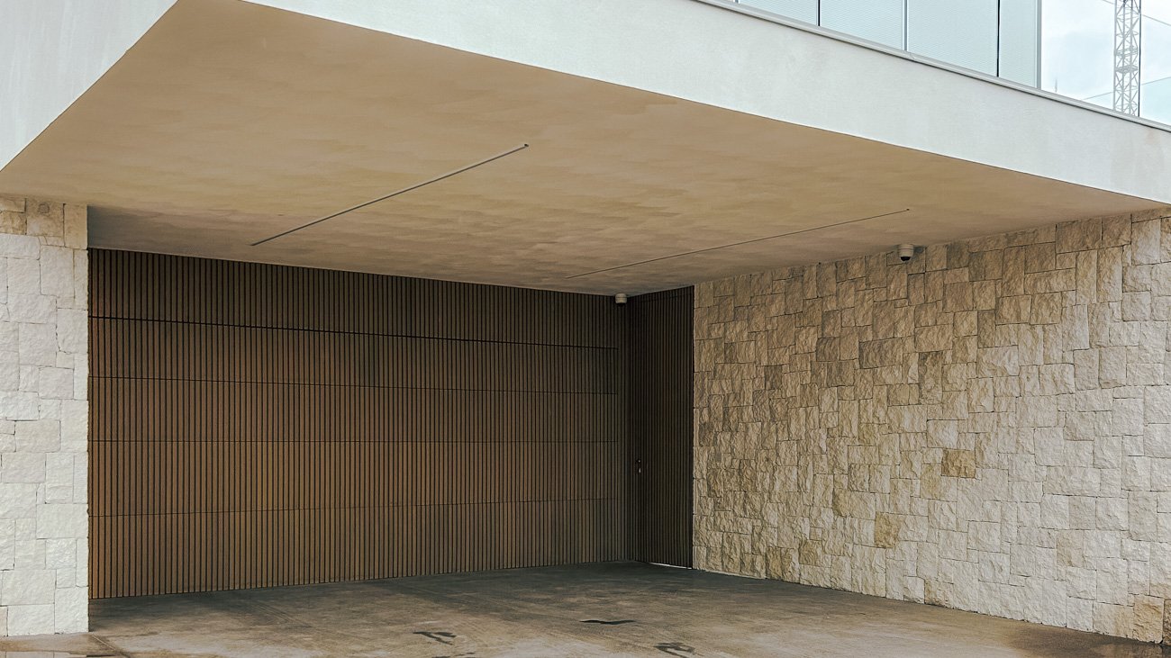 Entrada de garaje en un edificio con paredes de piedra y pared de madera de listones verticales.