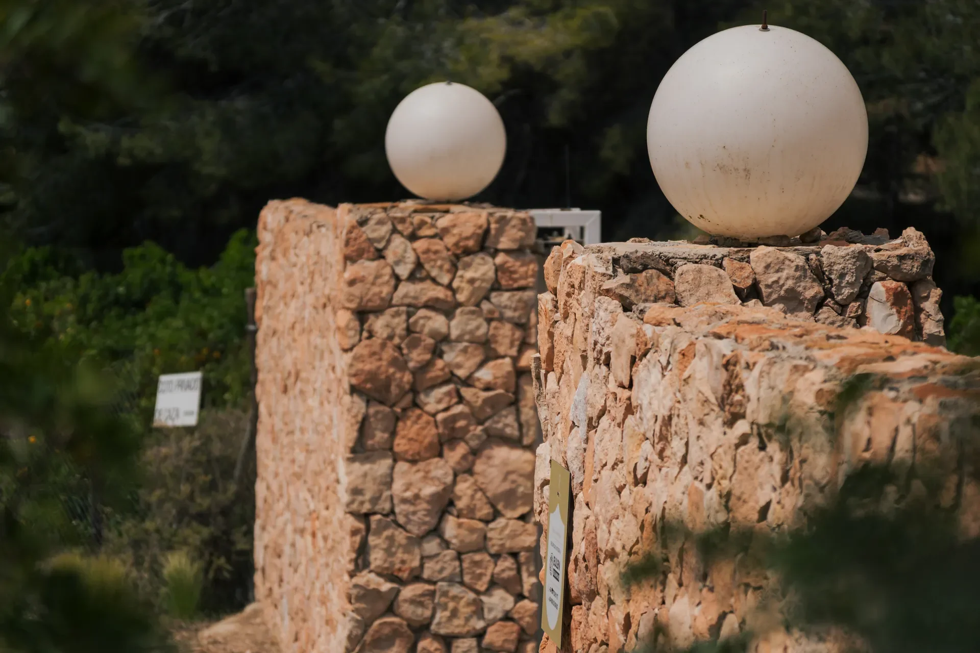 Fachada de casa con muro de piedra y puerta negra, entrada con escalón de piedra y sobrevuelo de concreto, cielo despejado.