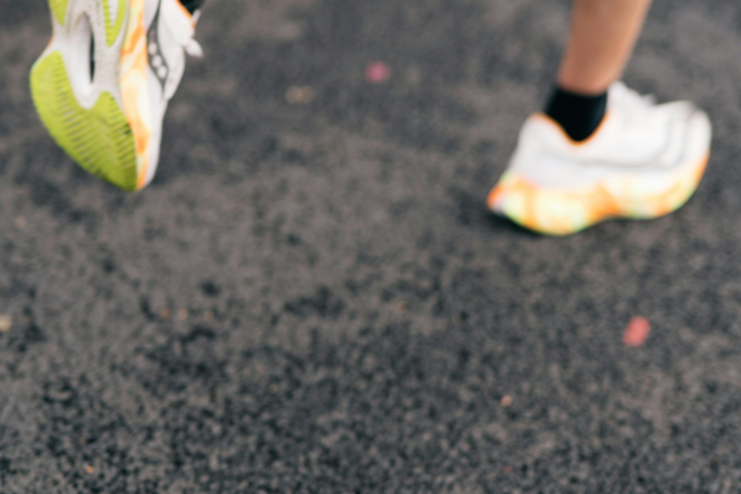 Close-up of a person's feet in running shoes on a gray athletic track surface.