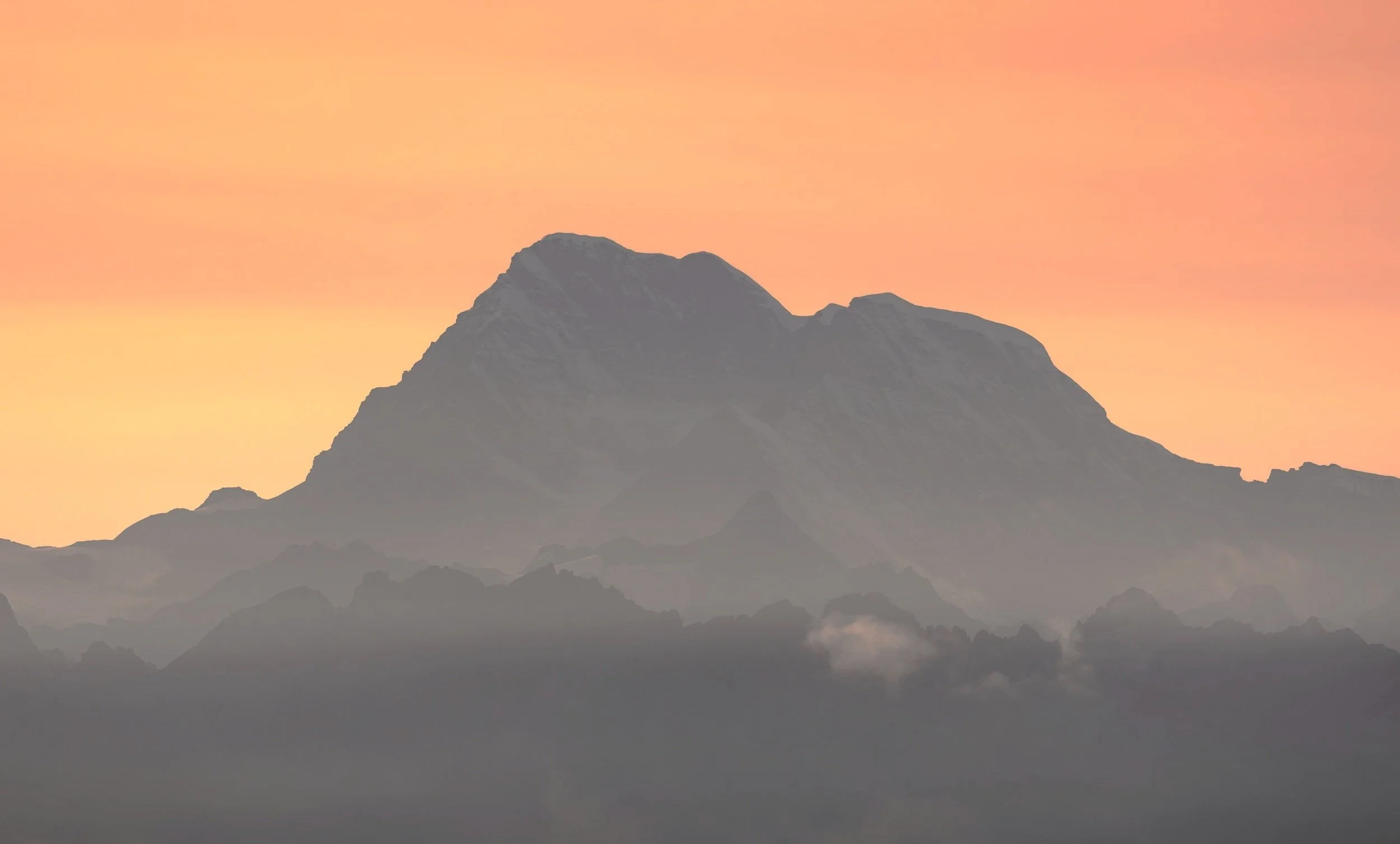 A mountain range during sunset with a pink and orange sky in the background.