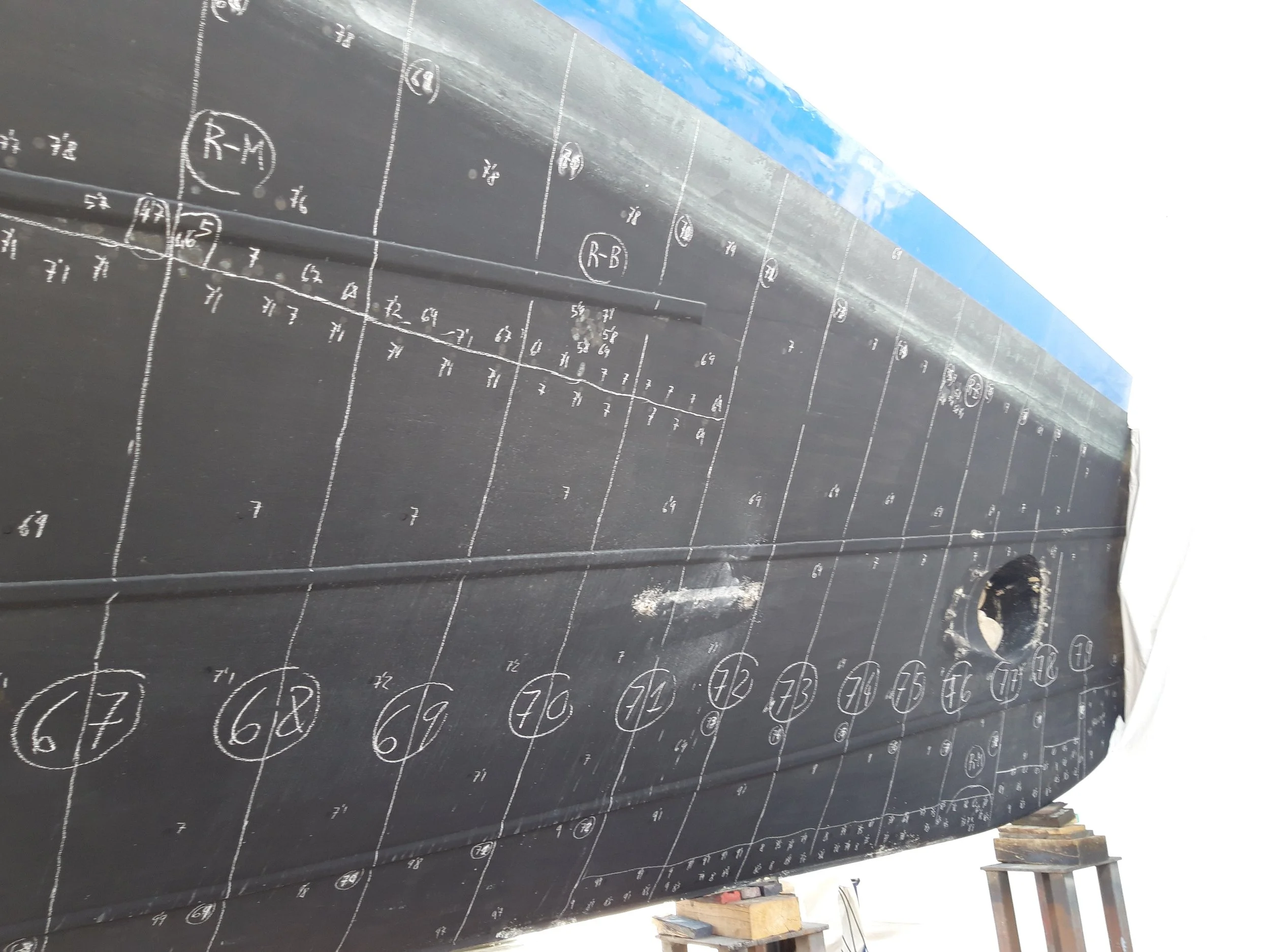 A close-up of a football field diagram drawn on a black surface with white chalk, showing yard lines, player positions, and formations.
