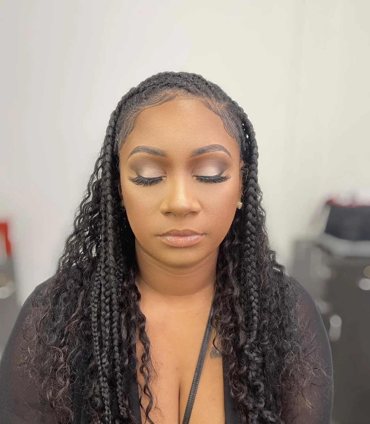 A woman with braided hair and makeup with closed eyes.