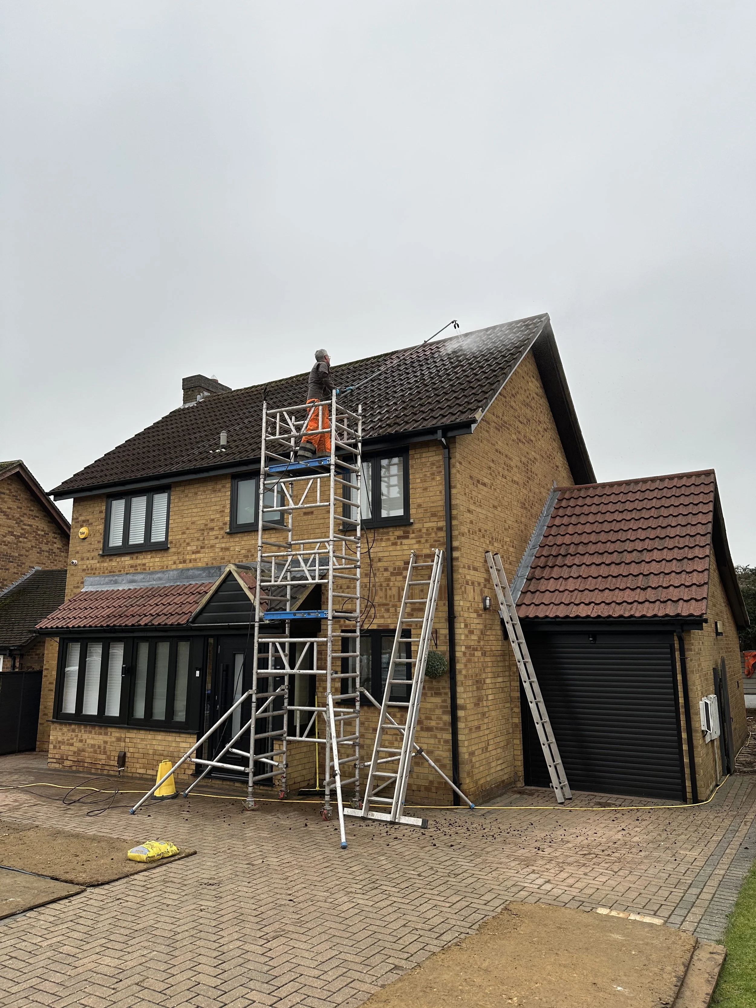 Low pressure washing a moss and dirt covered roof.