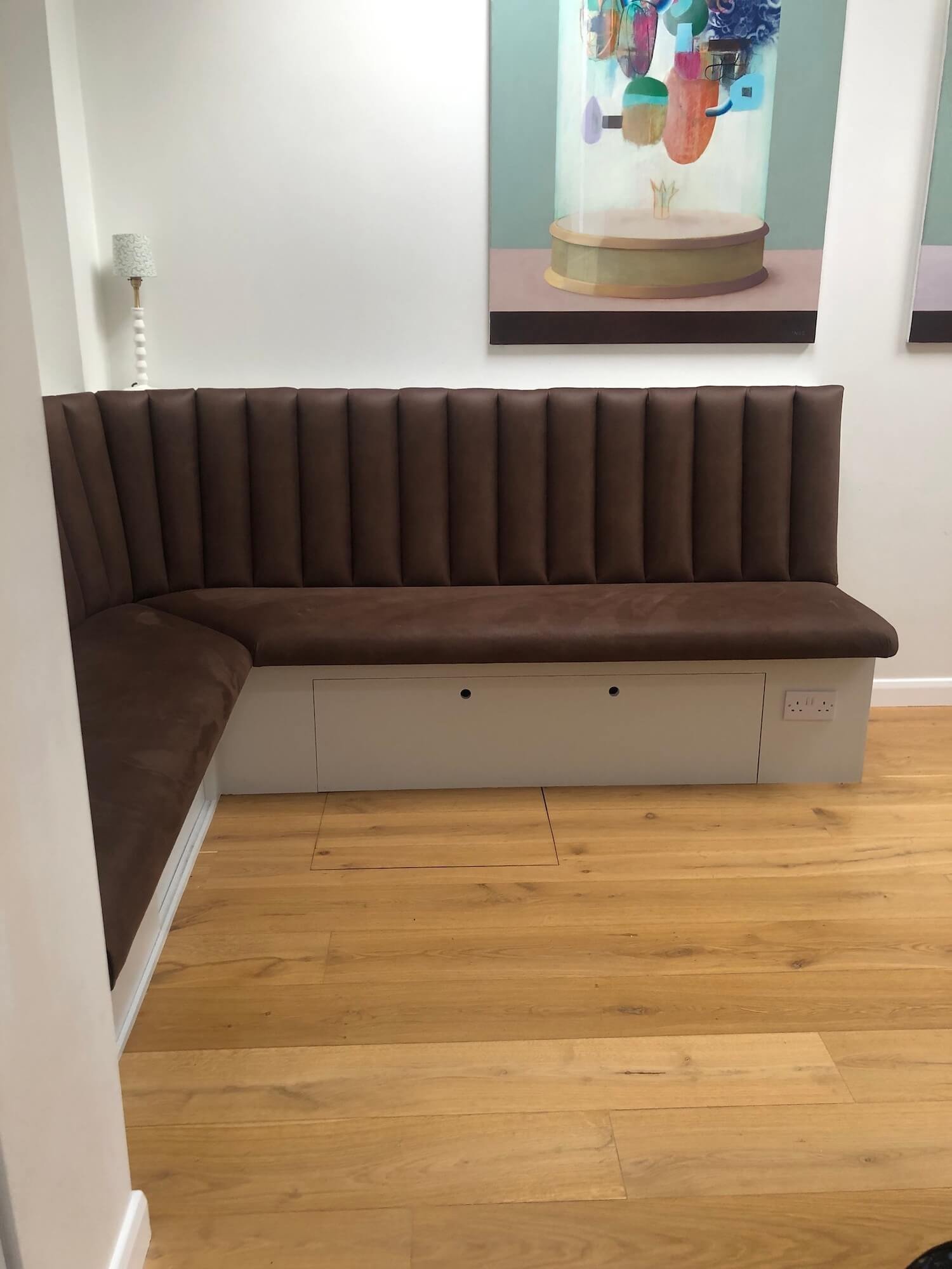 L-shaped banquette with brown upholstered seat and white base