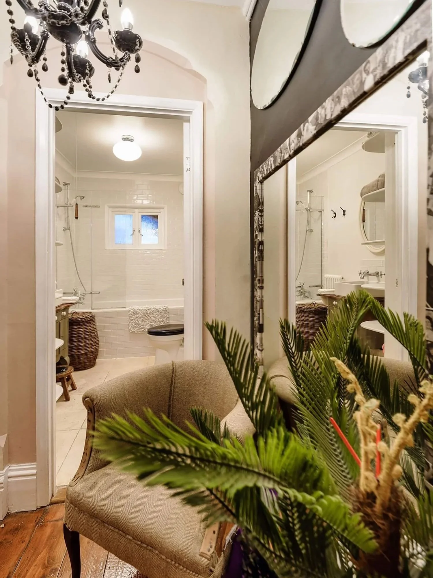 Entrance hallway with chandelier, large mirror and potted fern