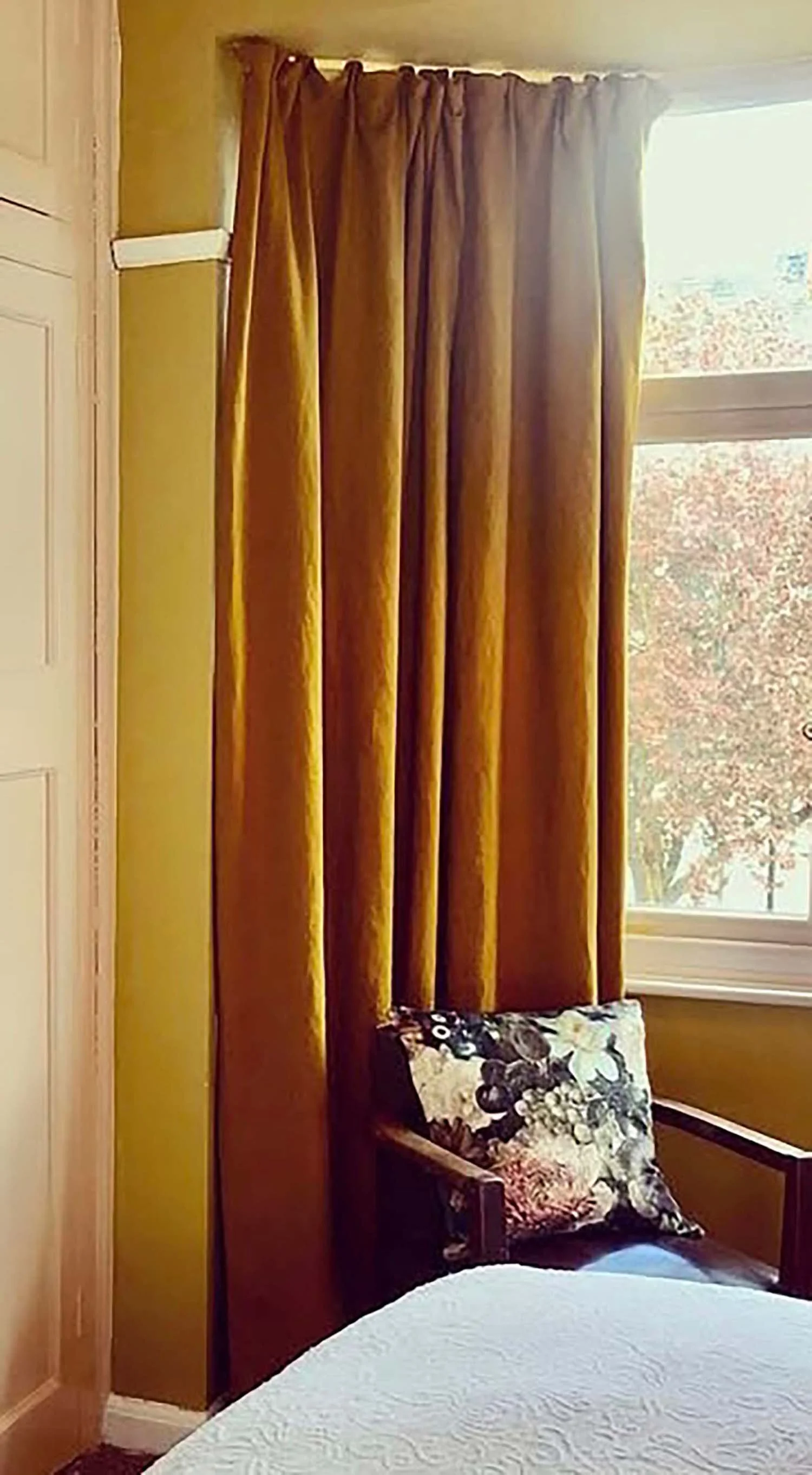 Draped gold curtains framing a reading nook with garden view
