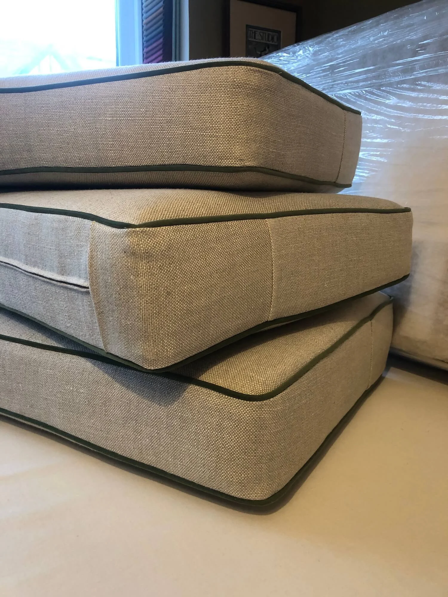 Stacked grey bench cushions with piped edges and tailored corners