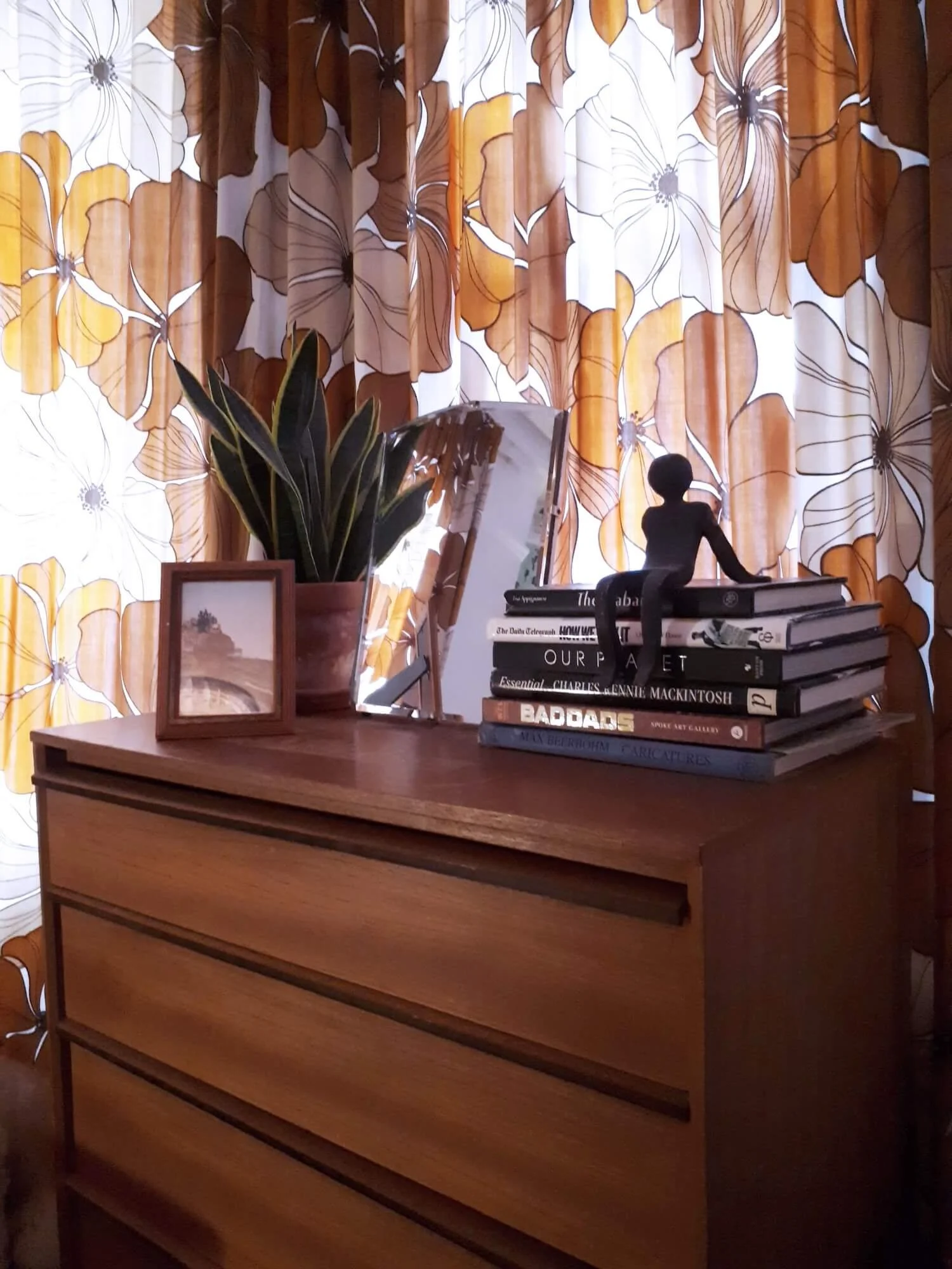 Close-up of mid-century chest of drawers styled with books and decorative objects