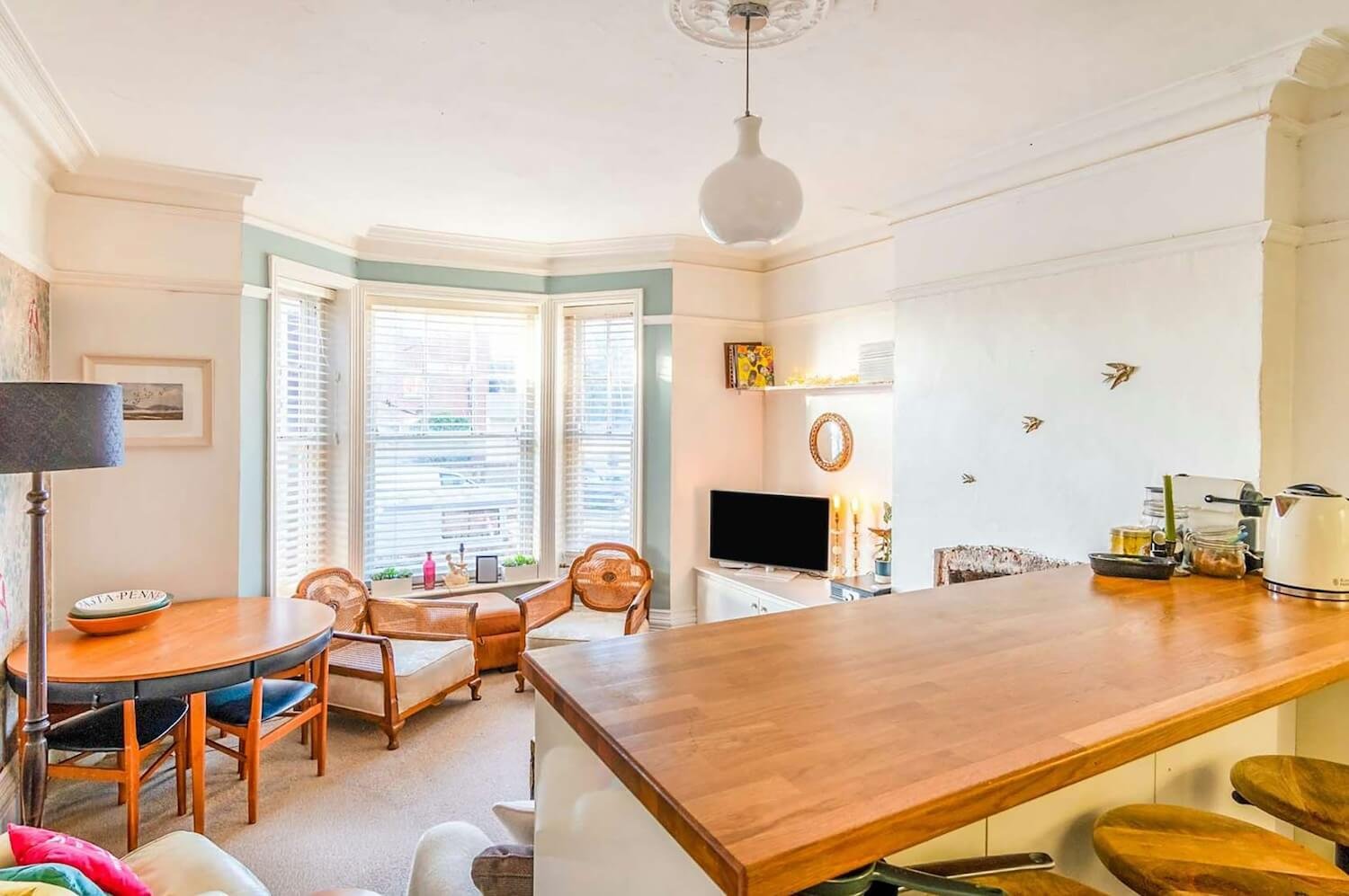 Open-plan dining and living area with wooden table and original fireplace