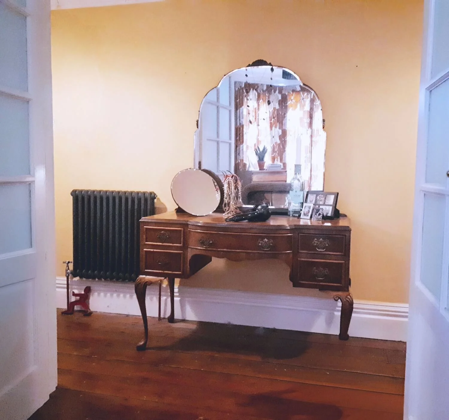 Vintage dressing table with arched mirror and wooden stool in soft yellow room