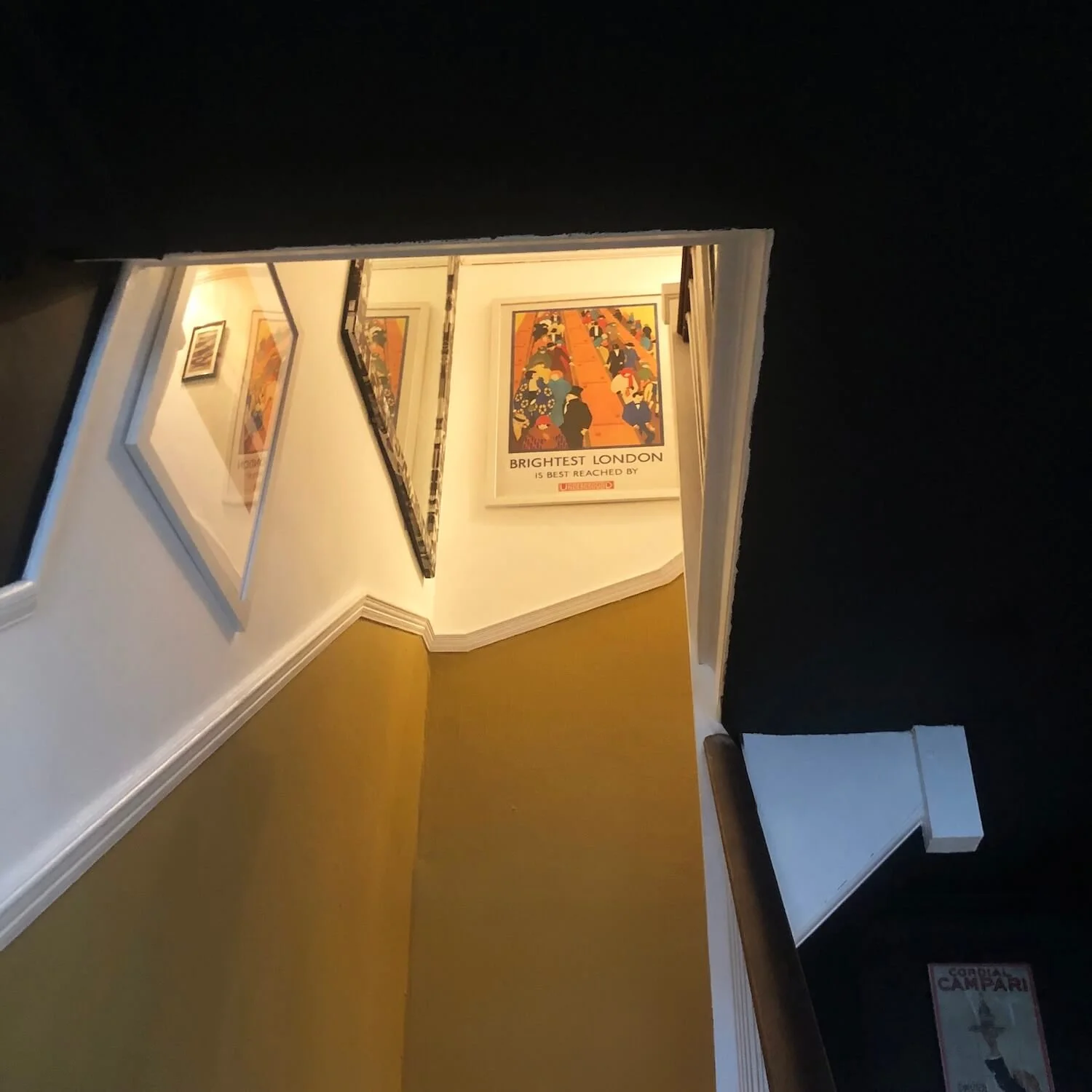 Staircase with striking gallery wall of colourful framed artwork