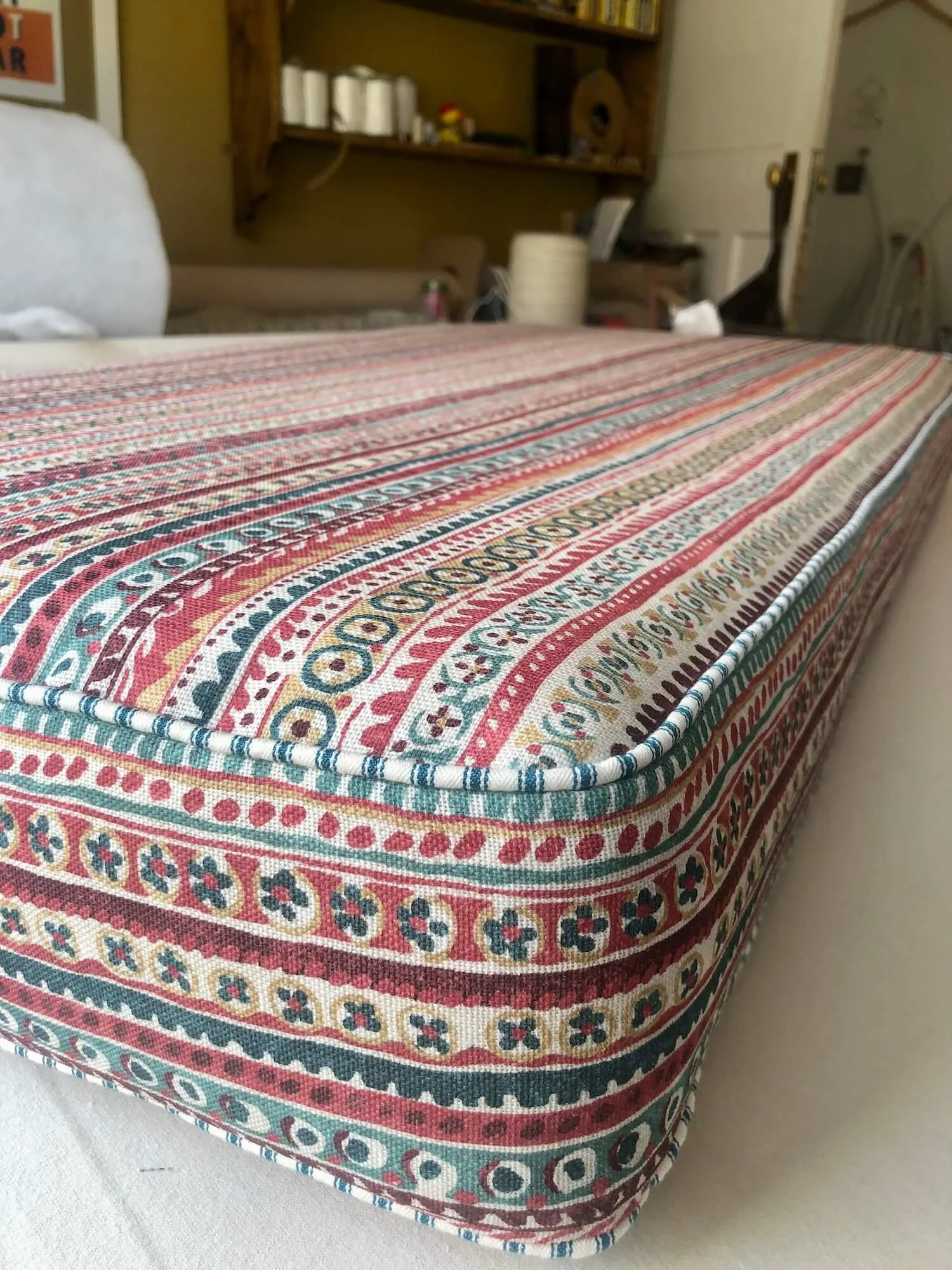Striped patterned bench cushion with red, blue and cream detailing