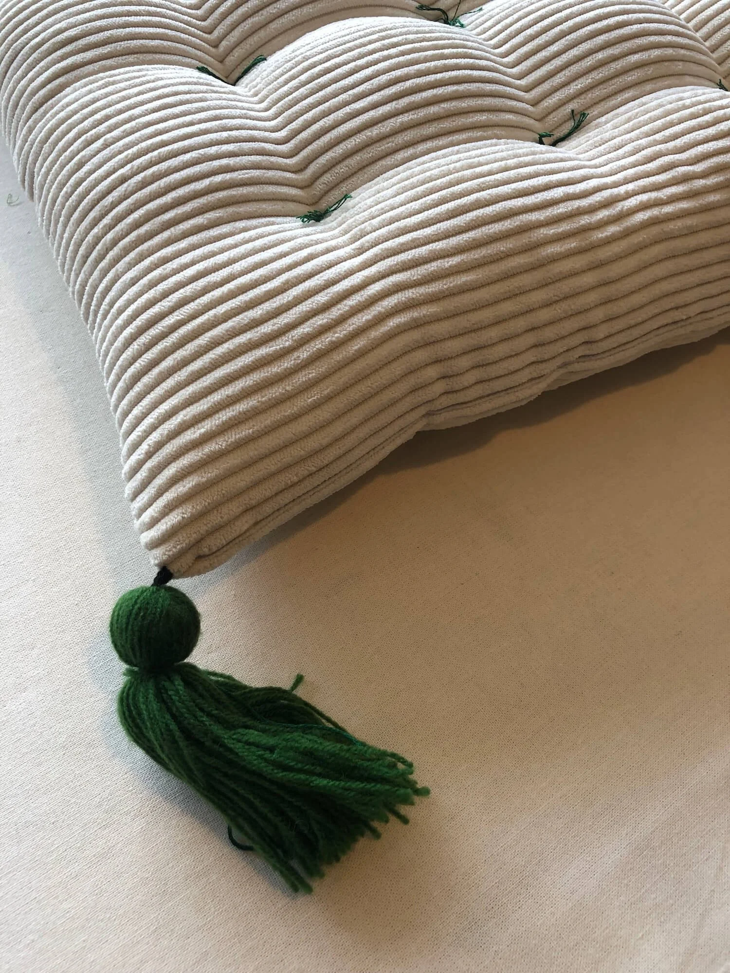 Tufted cushion detail with striped fabric and tassel corner