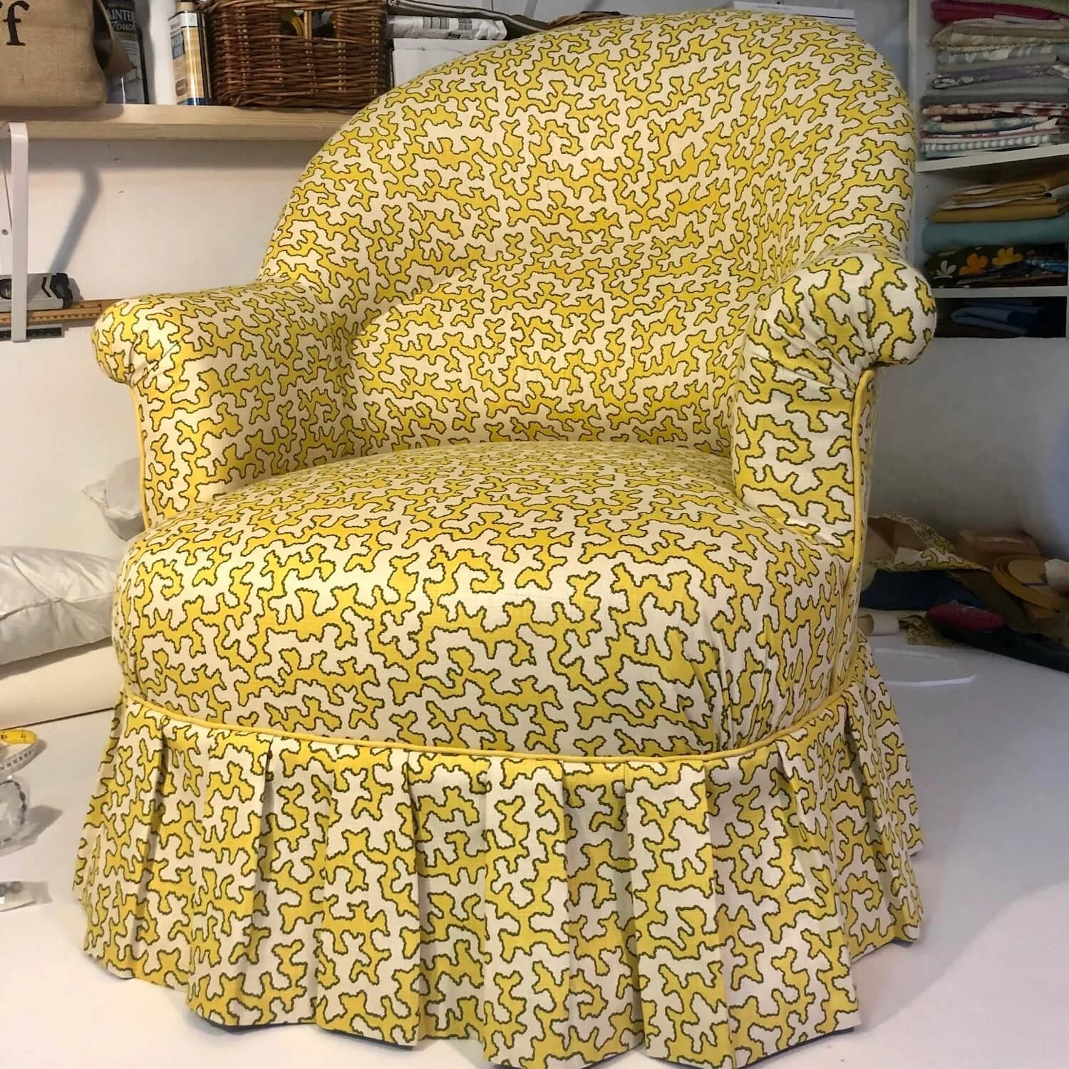 Yellow patterned armchair with pleated skirt after reupholstery