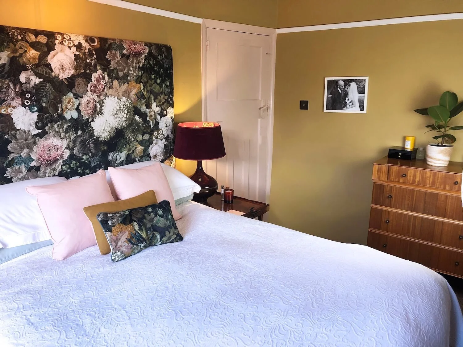Bedroom featuring floral headboard, blue cushions and warm wood furniture